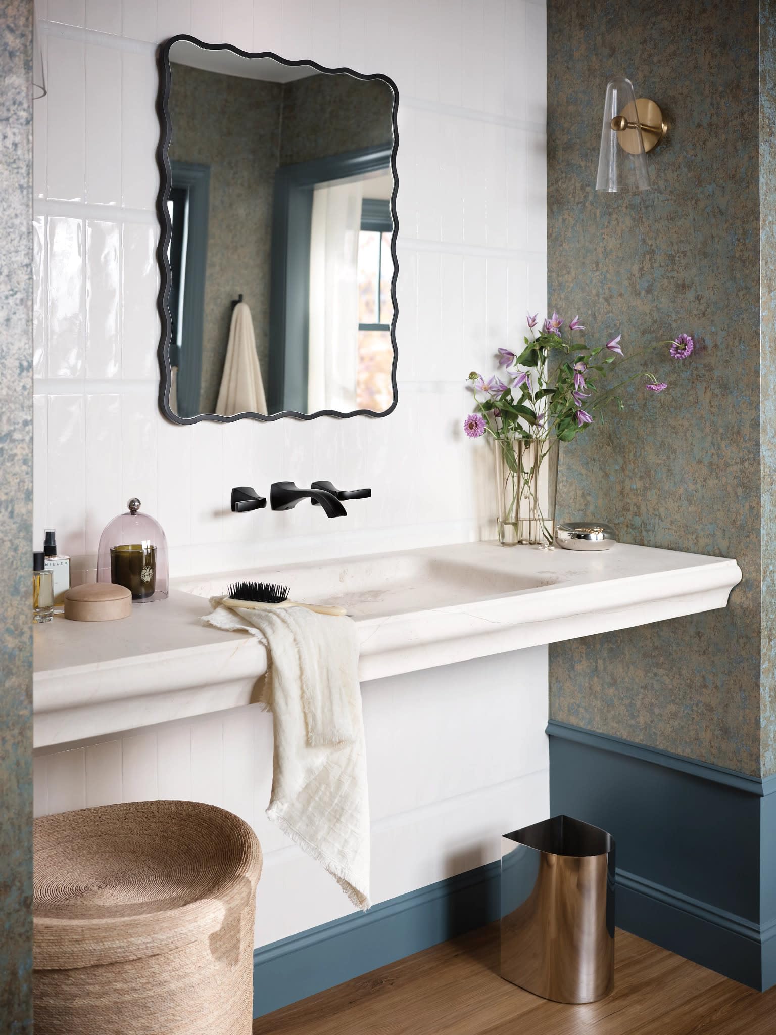Matte black two-handle wall-mounted bathroom faucet with curved spout installed above white sink.