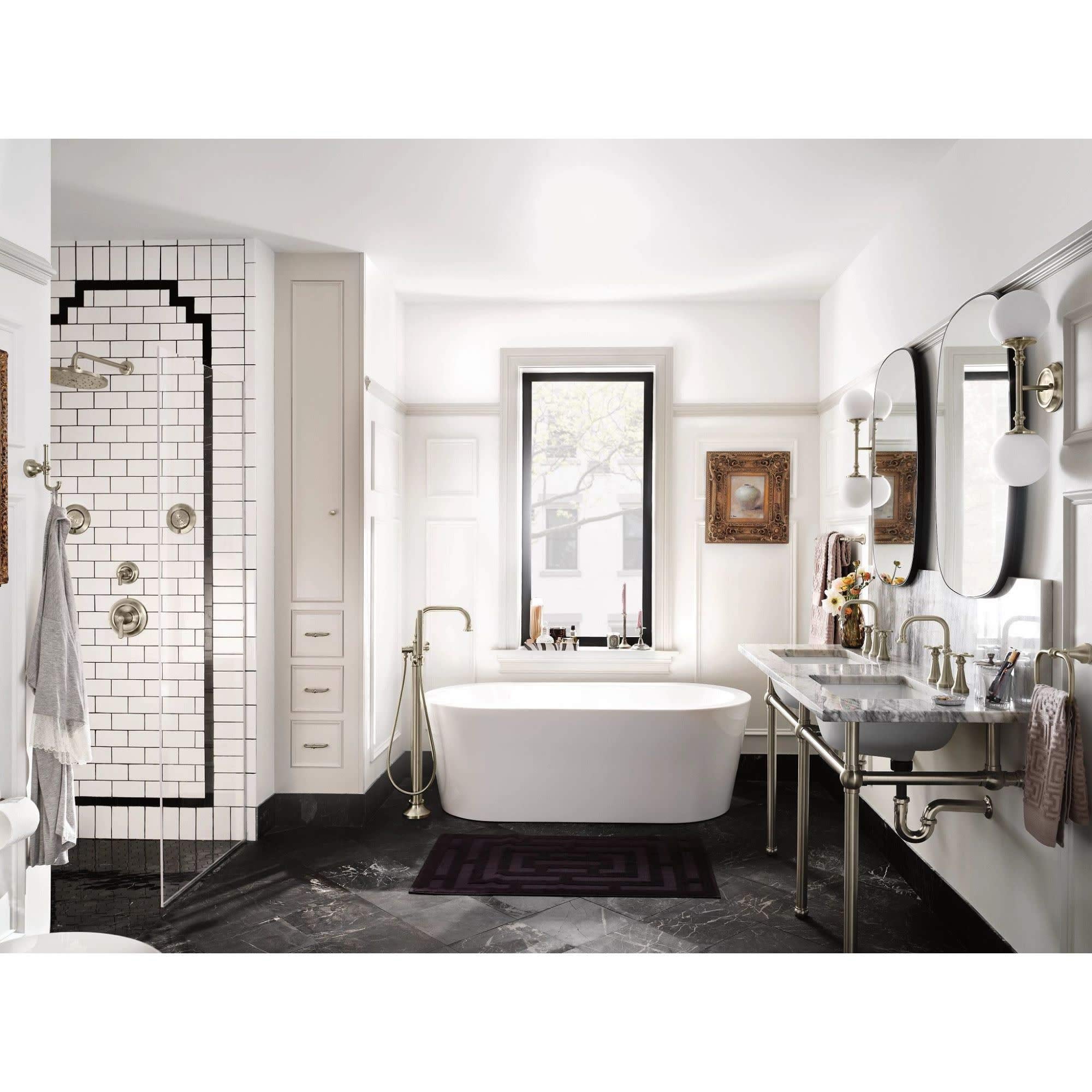 Matte black freestanding tub filler with single handle and curved spout positioned beside white oval bathtub.