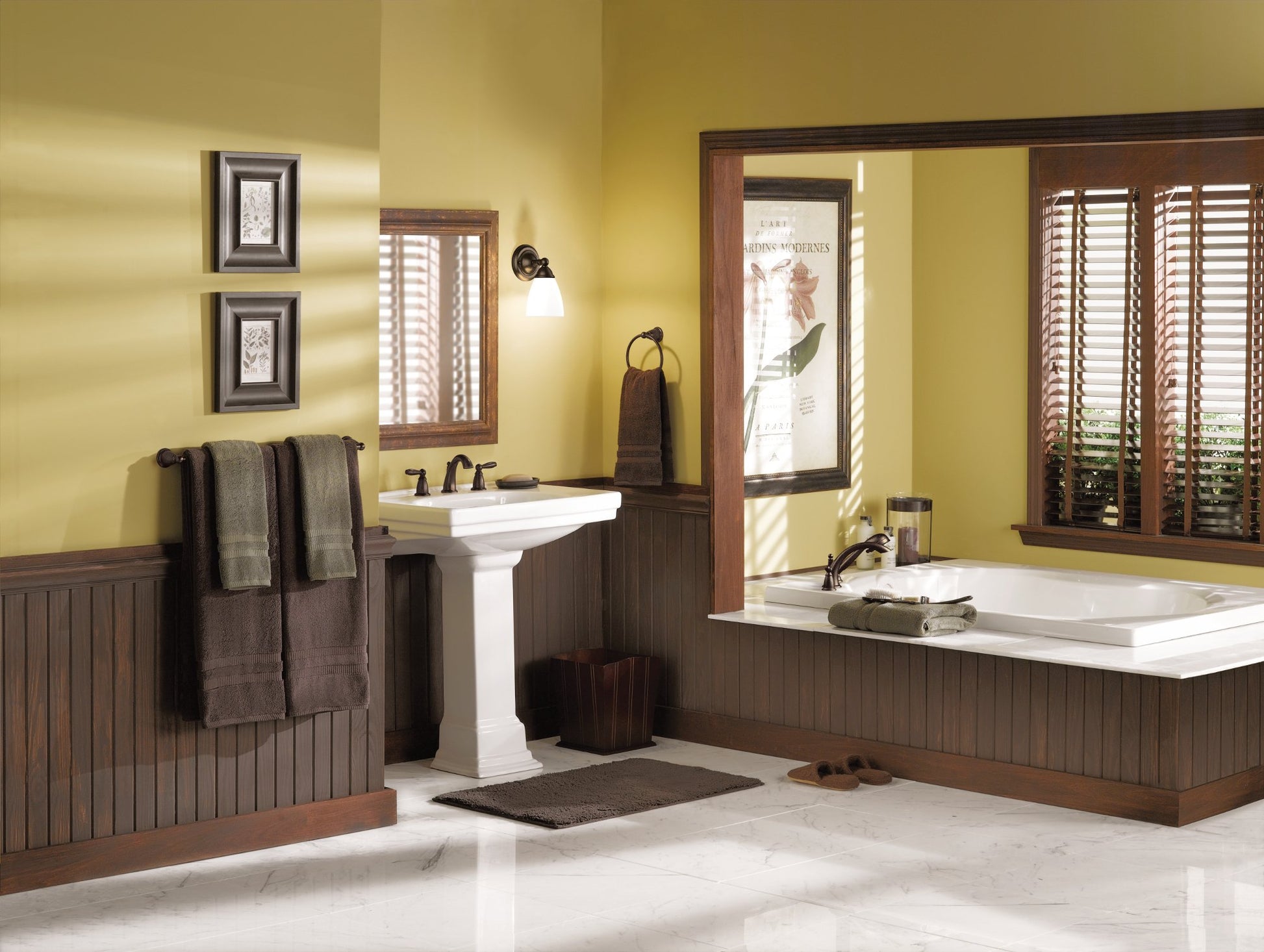 Oil-rubbed bronze two-handle Roman tub faucet trim kit with handshower mounted on white deck in bathroom setting.