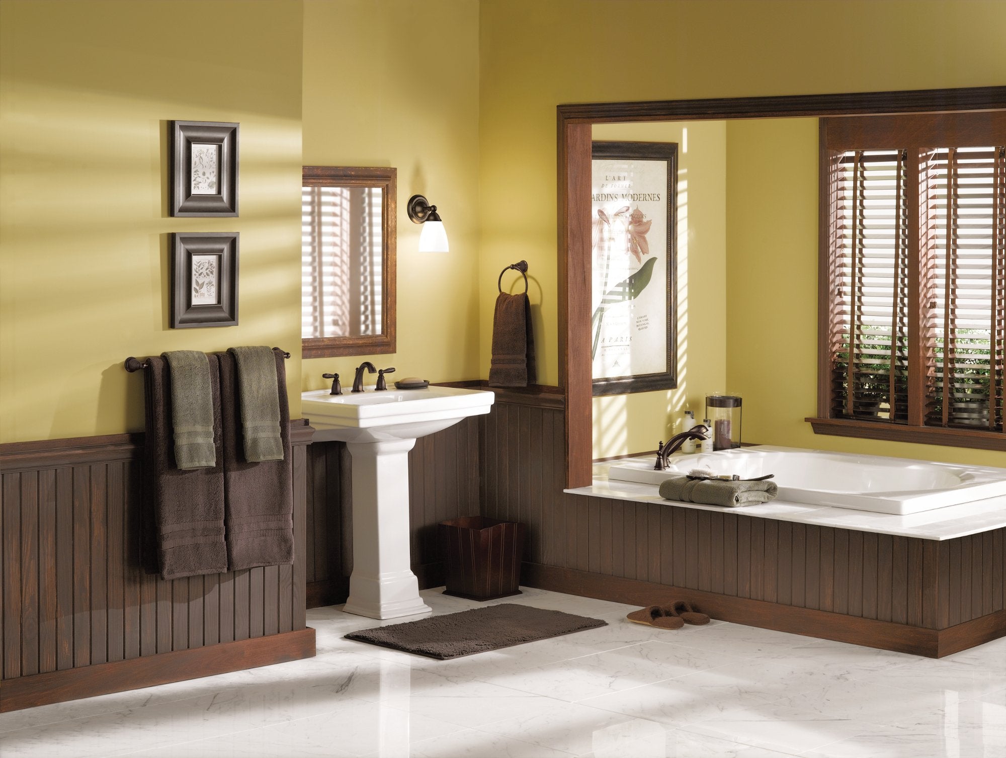 Oil-rubbed bronze two-handle Roman tub faucet trim kit with handshower mounted on white deck in bathroom setting.