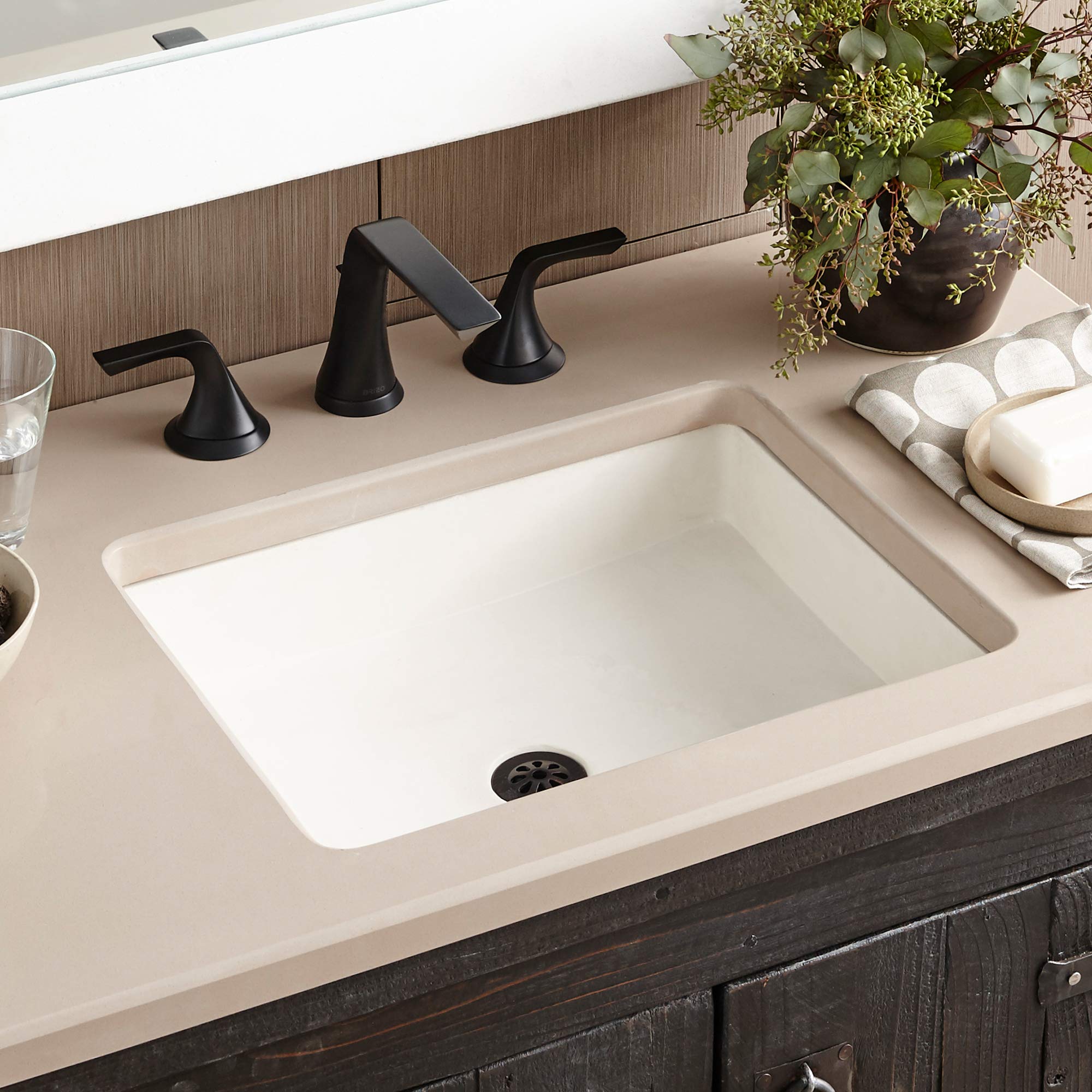 Pearl white rectangular undermount bathroom sink with black three-hole faucet mounted on countertop.