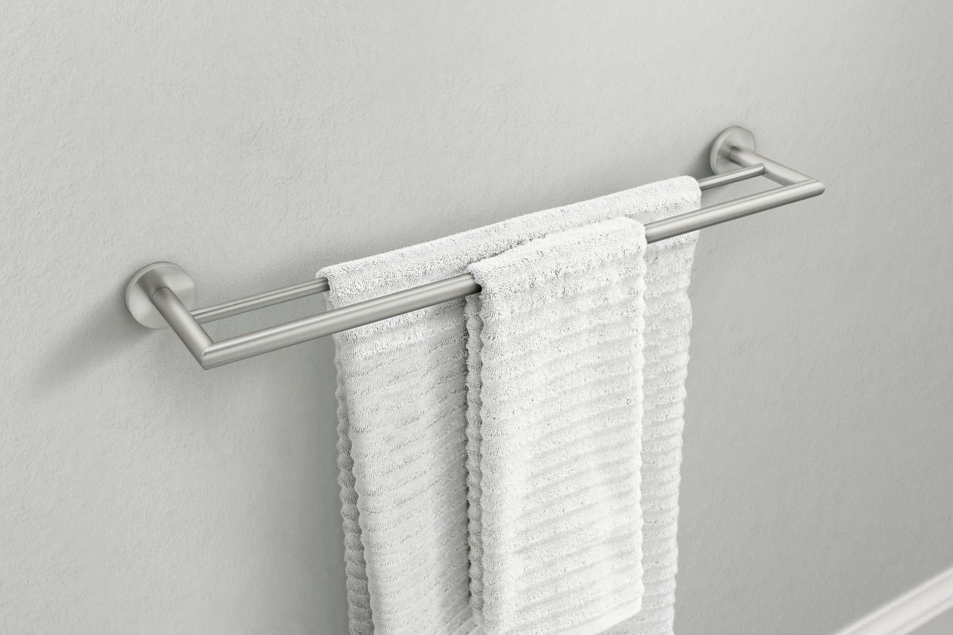 Brushed nickel double towel bar mounted on wall with two white towels draped over parallel bars.