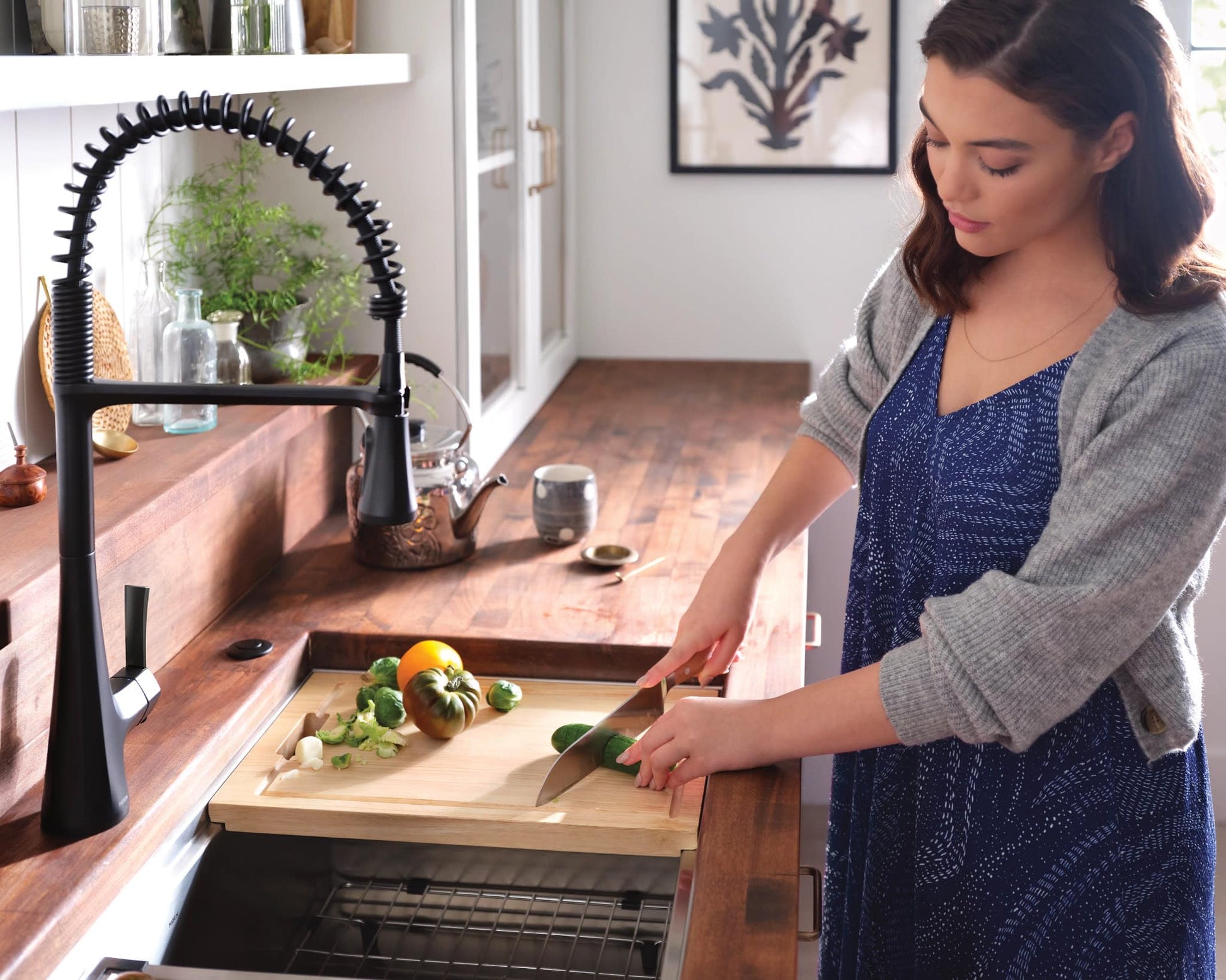 Matte black single-handle pulldown kitchen faucet with coiled spring hose installed above wooden sink counter.