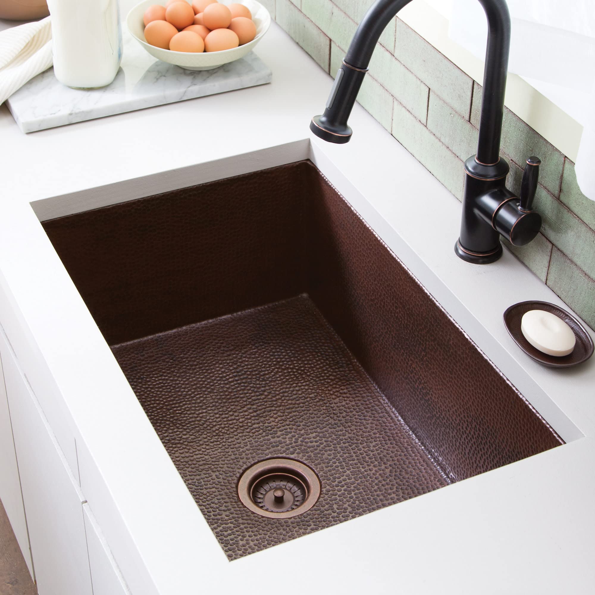 Rectangular undermount kitchen sink with textured dark bronze basin, single drain, and black pull-down faucet in white counte