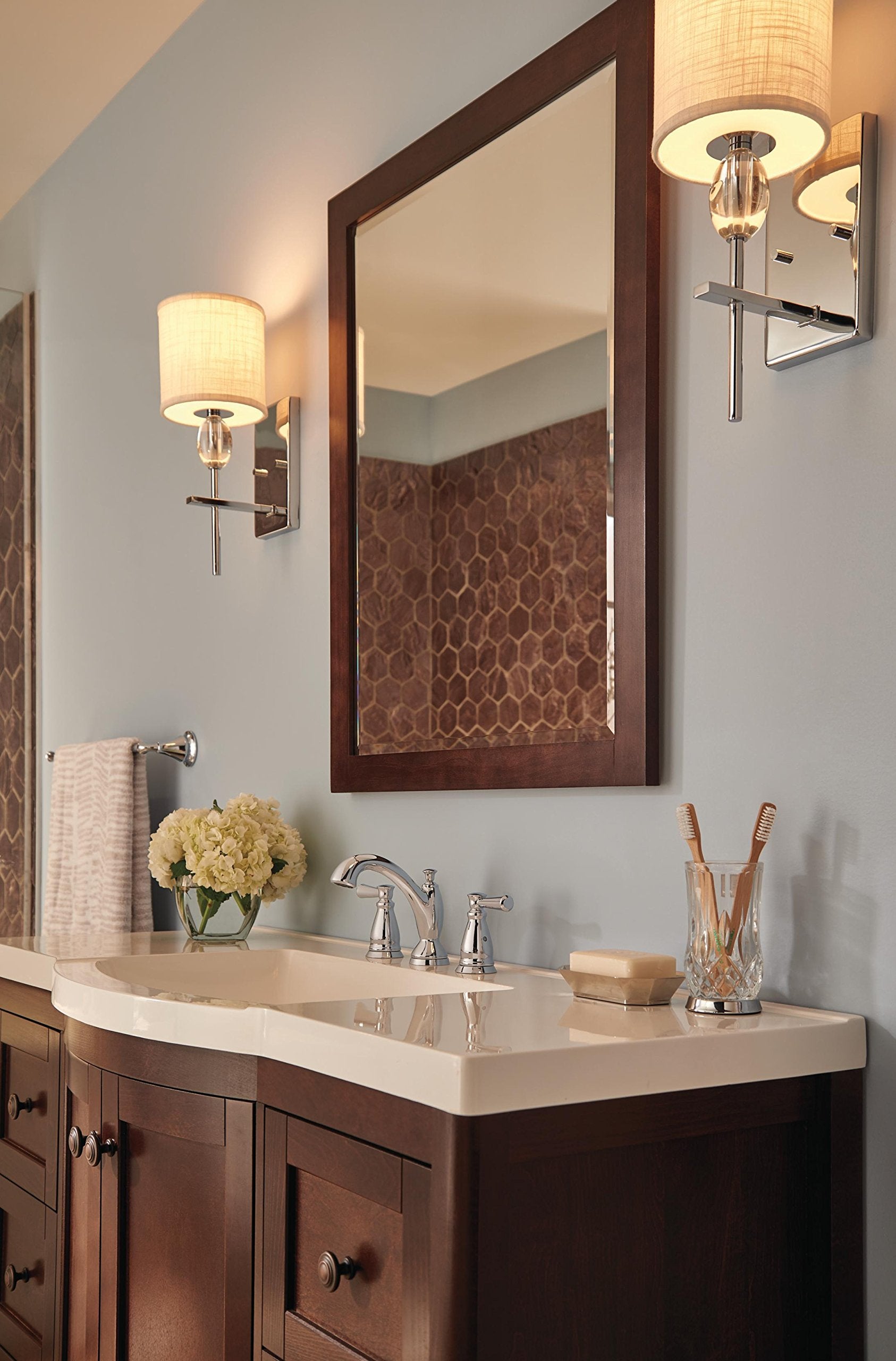 Chrome two-handle widespread bathroom faucet with curved spout installed on beige countertop sink.