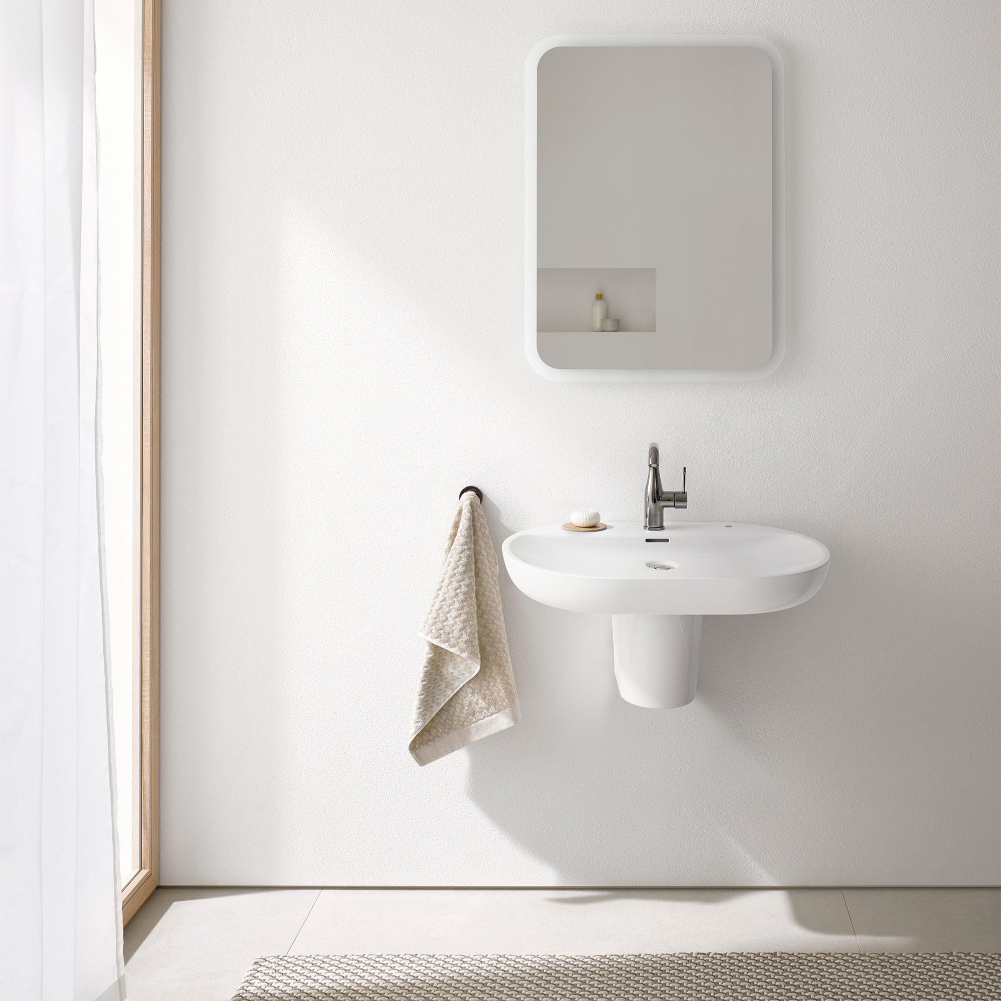 Hard graphite single-handle bathroom faucet mounted on white pedestal sink with rounded basin.