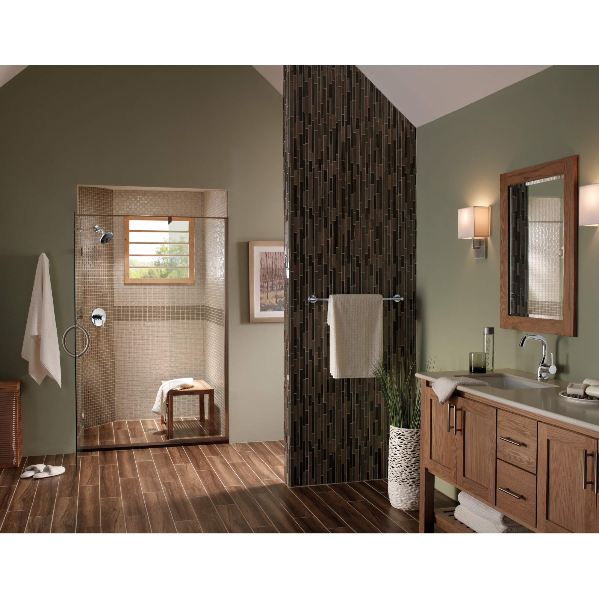Chrome robe hook mounted on black tile wall in bathroom with towel draped over it.
