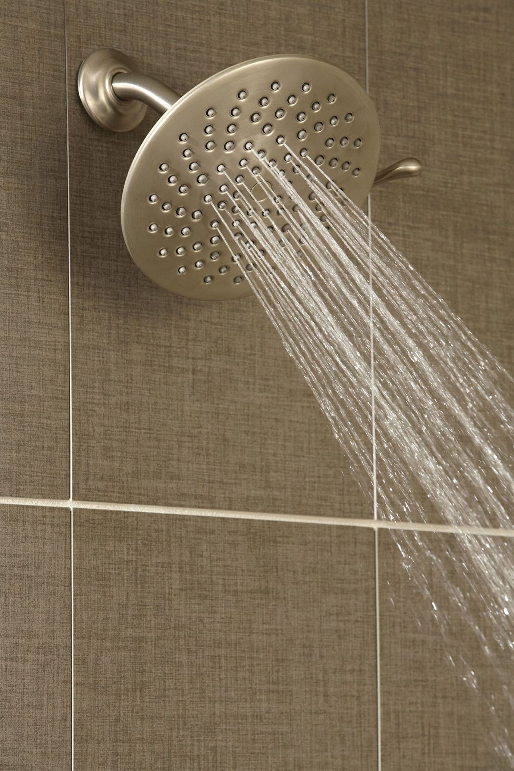 Brushed nickel 8-inch circular rainshower head mounted on wall with water streaming downward from multiple jets.
