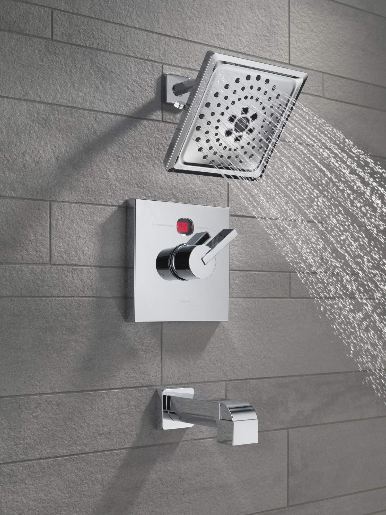 Champagne bronze tub spout with pull-up diverter mounted on tile wall below showerhead and valve controls.