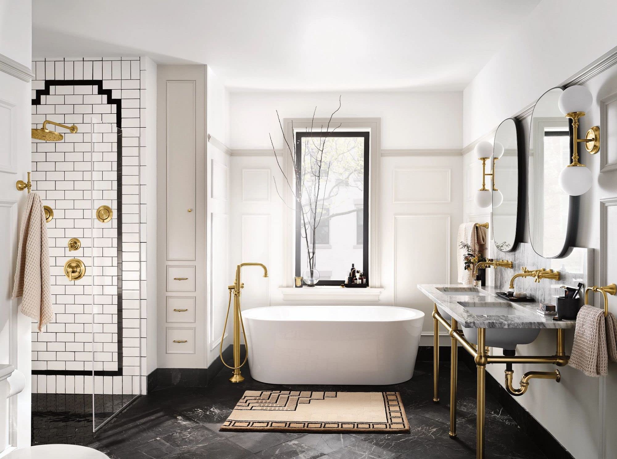 Brushed gold single-handle valve trim kit installed on white subway tile shower wall in modern bathroom.
