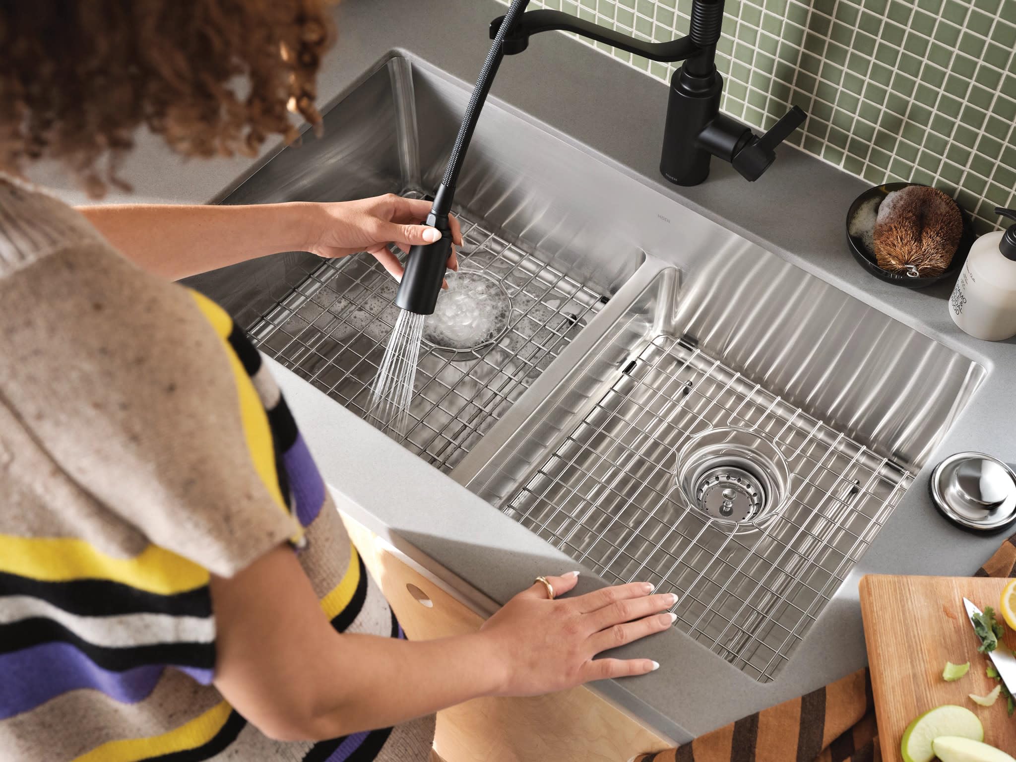 Matte black single-handle kitchen faucet with pull-down sprayer extended over stainless steel double sink basin.