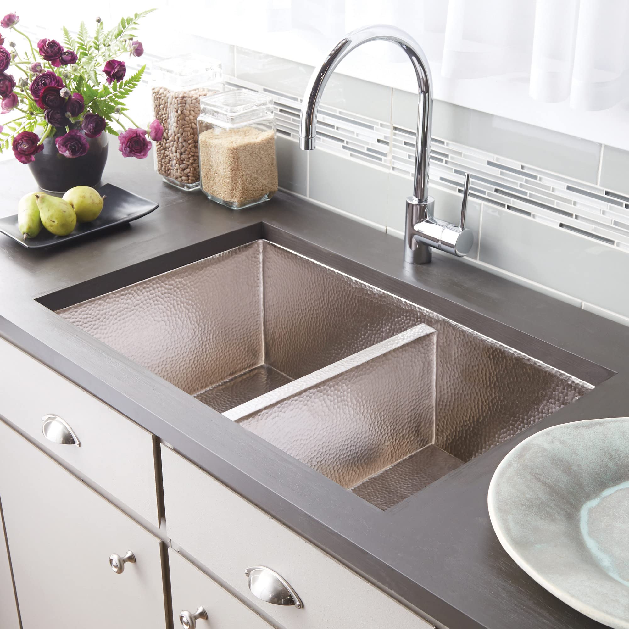 Antique copper double-basin kitchen sink with hammered finish and chrome faucet installed in gray countertop.