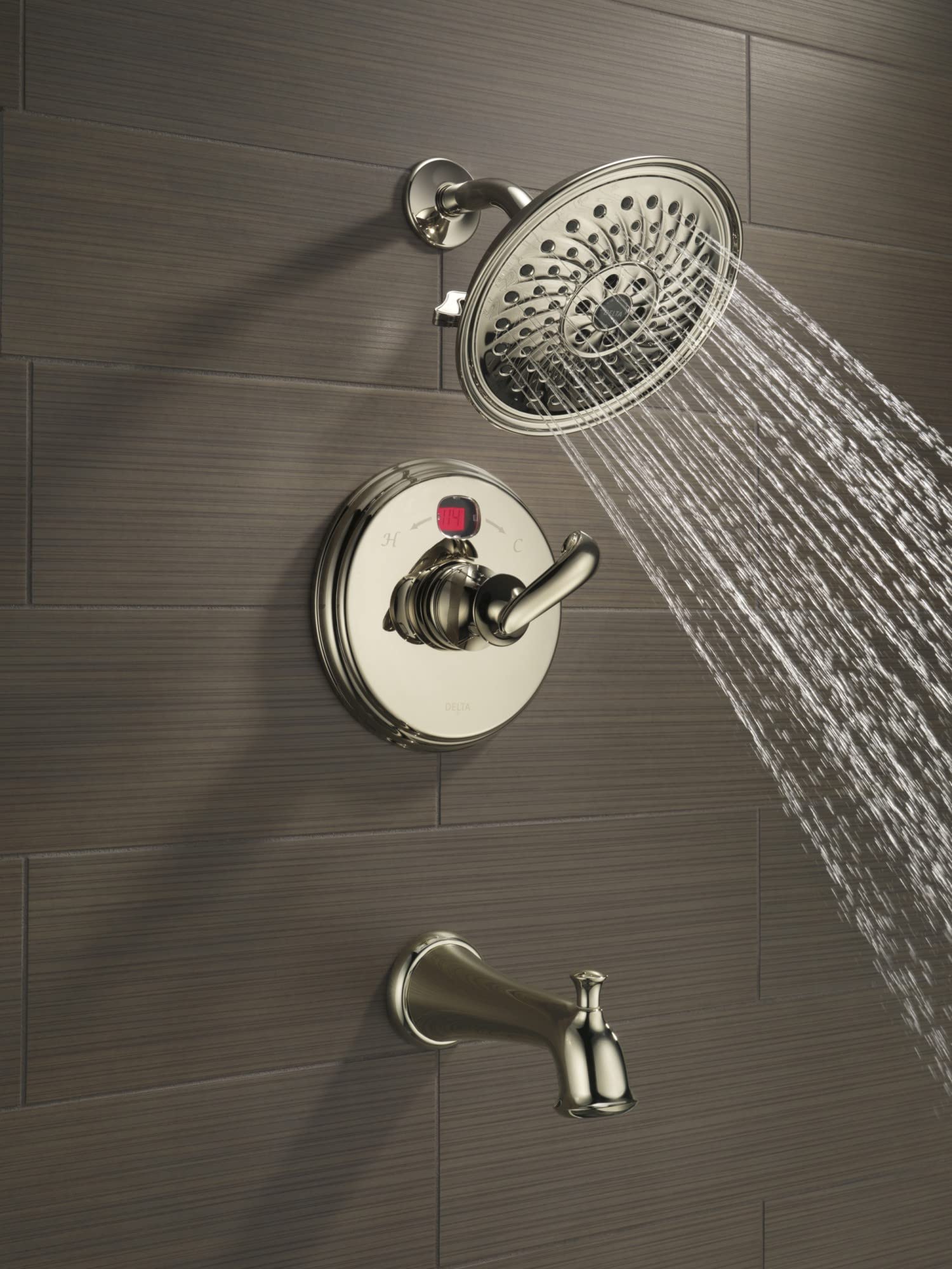 Chrome tub spout with pull-up diverter installed on tile wall with matching showerhead and valve trim.