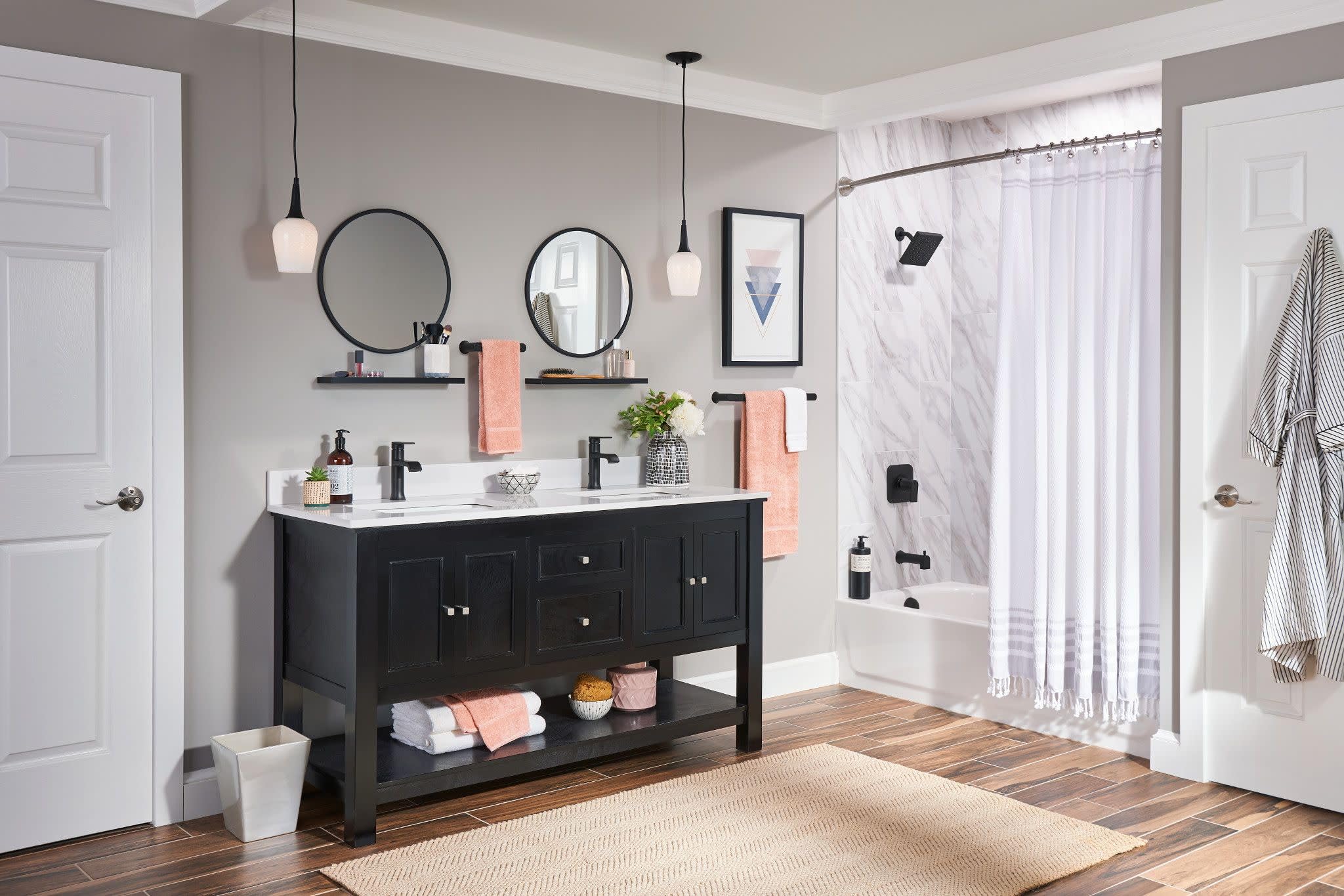 Matte black single handle faucet mounted on white sink vanity in bathroom with dual circular mirrors.