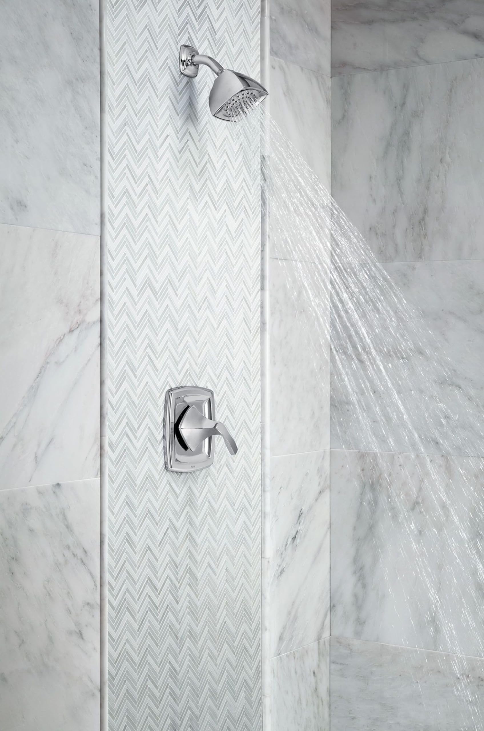 Chrome shower valve trim with single handle and rainfall showerhead mounted on marble tile wall with water flowing.