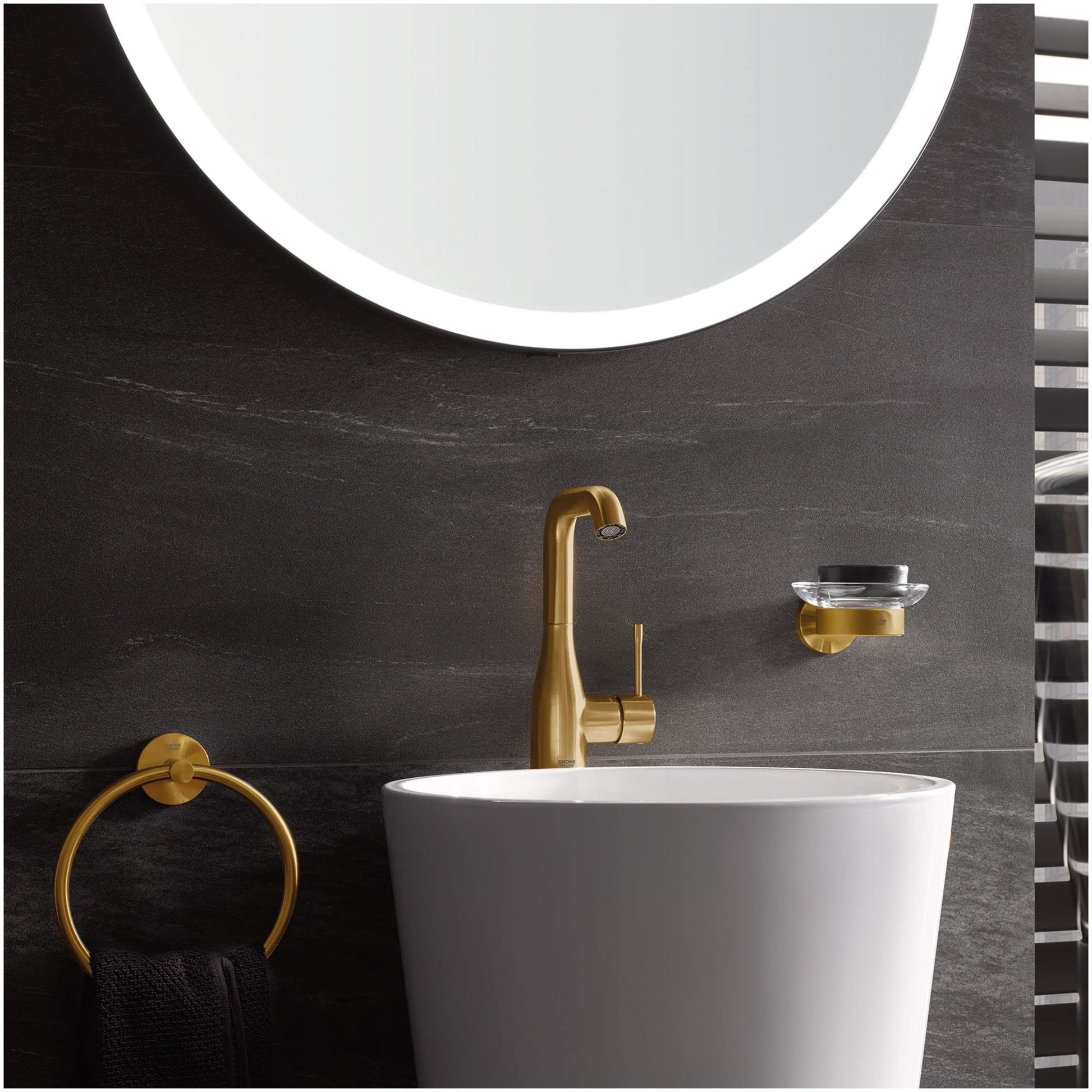 Matte black circular towel ring mounted on dark tile wall in bathroom setting.
