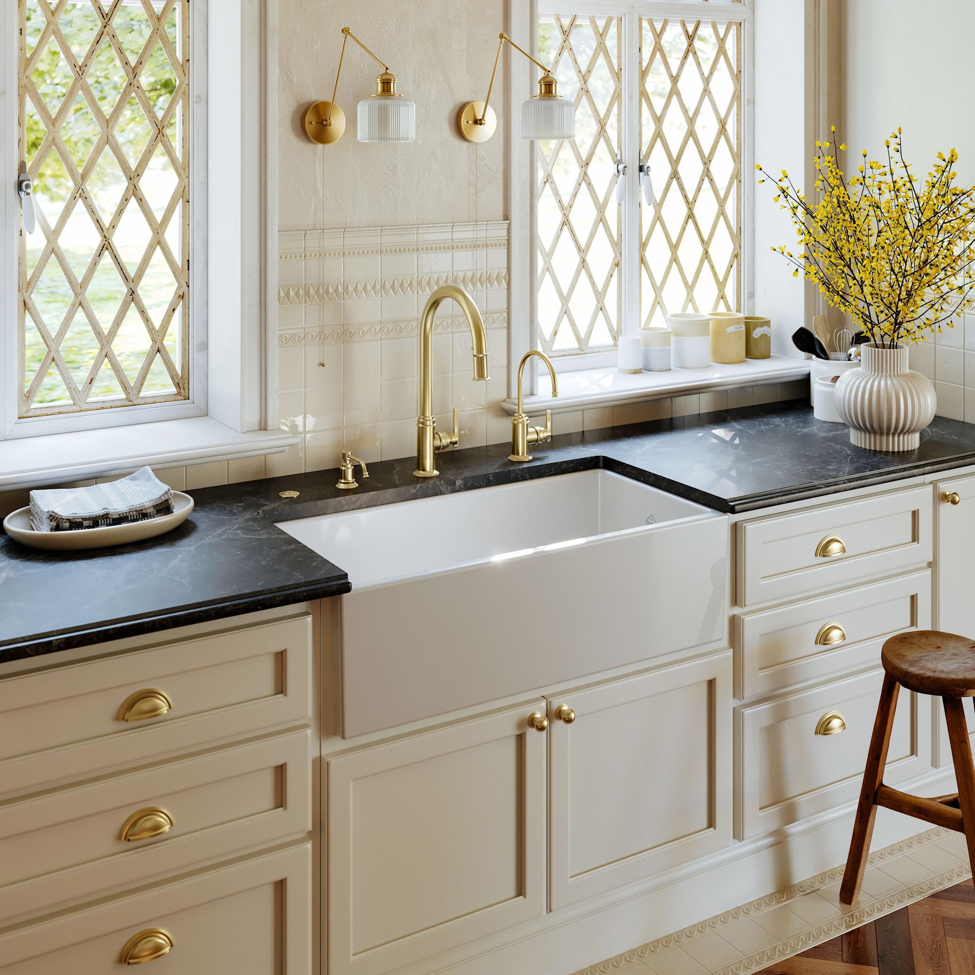 White fireclay farmhouse apron front kitchen sink with single bowl installed in cream cabinetry with black countertop.