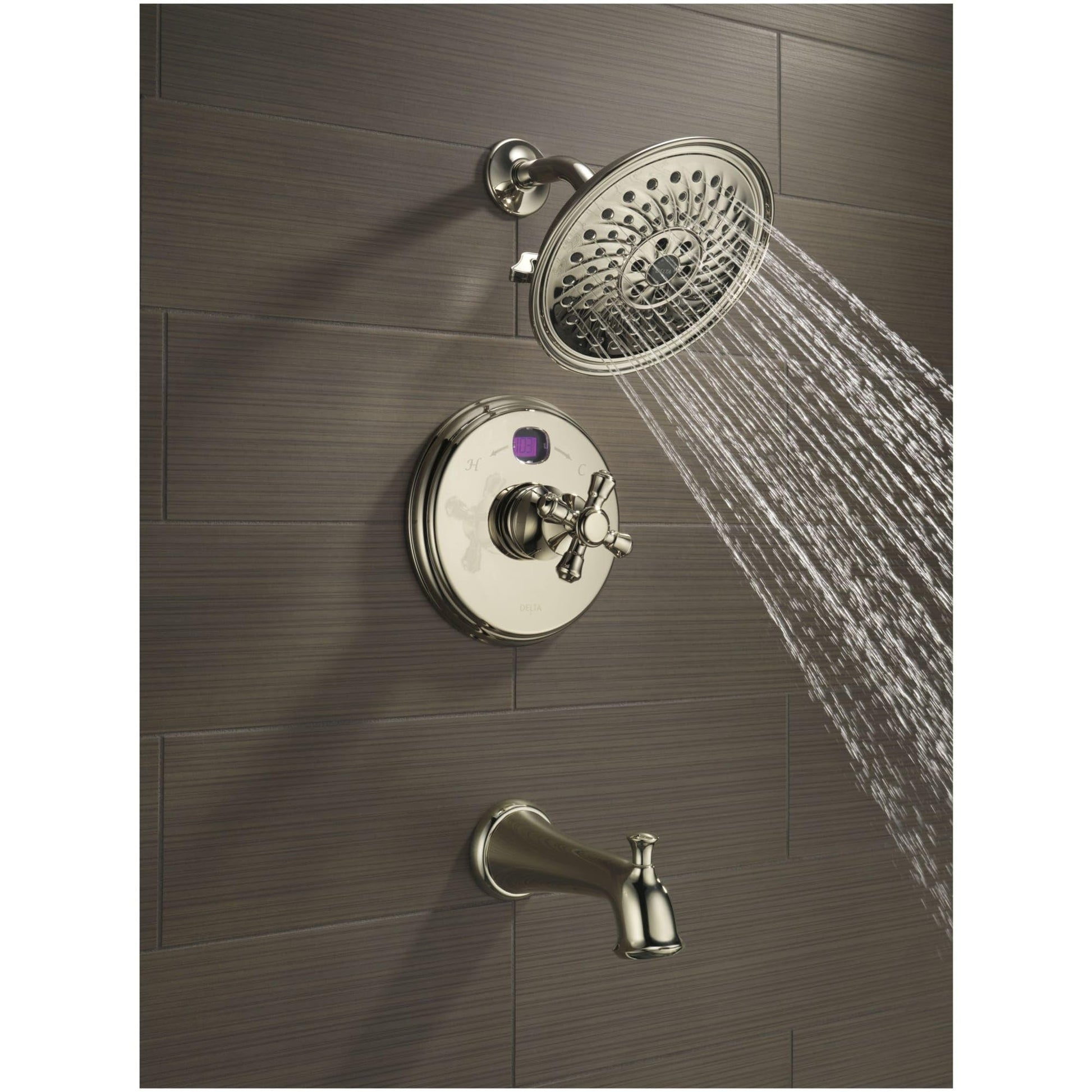 Polished nickel shower system with round showerhead, control valve, and tub spout mounted on gray tile wall.