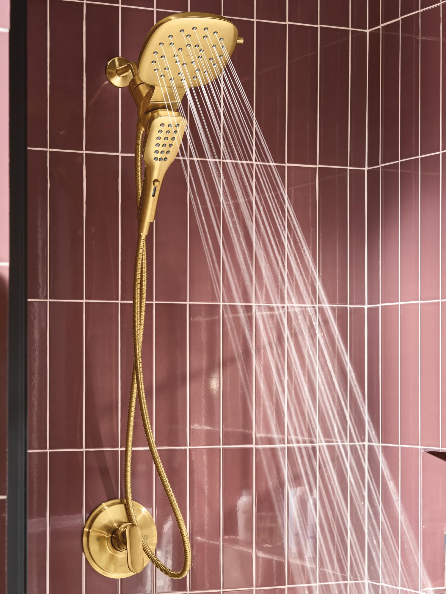 Brushed gold shower system with square overhead head and detachable handheld spray mounted on tiled bathroom wall.