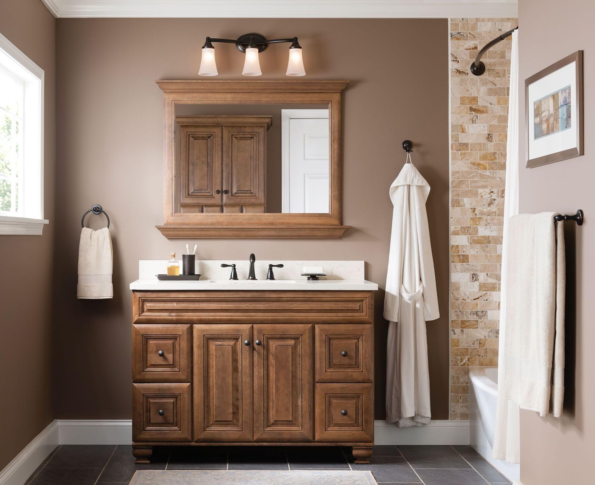 Three-light vanity fixture with oil-rubbed bronze frame and frosted glass shades mounted above bathroom sink.