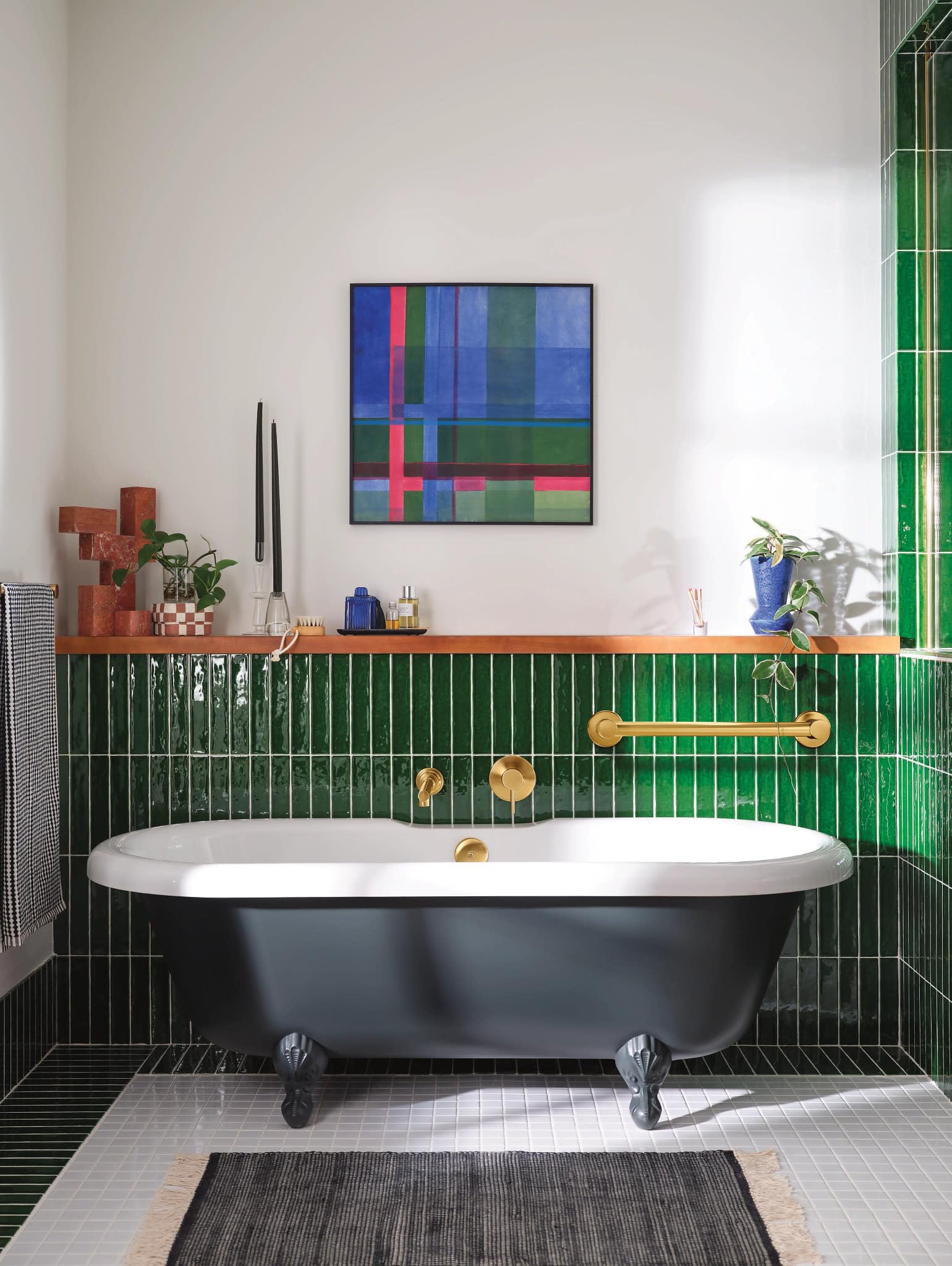 Brushed gold wall-mounted tub faucet with single handle and curved spout above freestanding bathtub.
