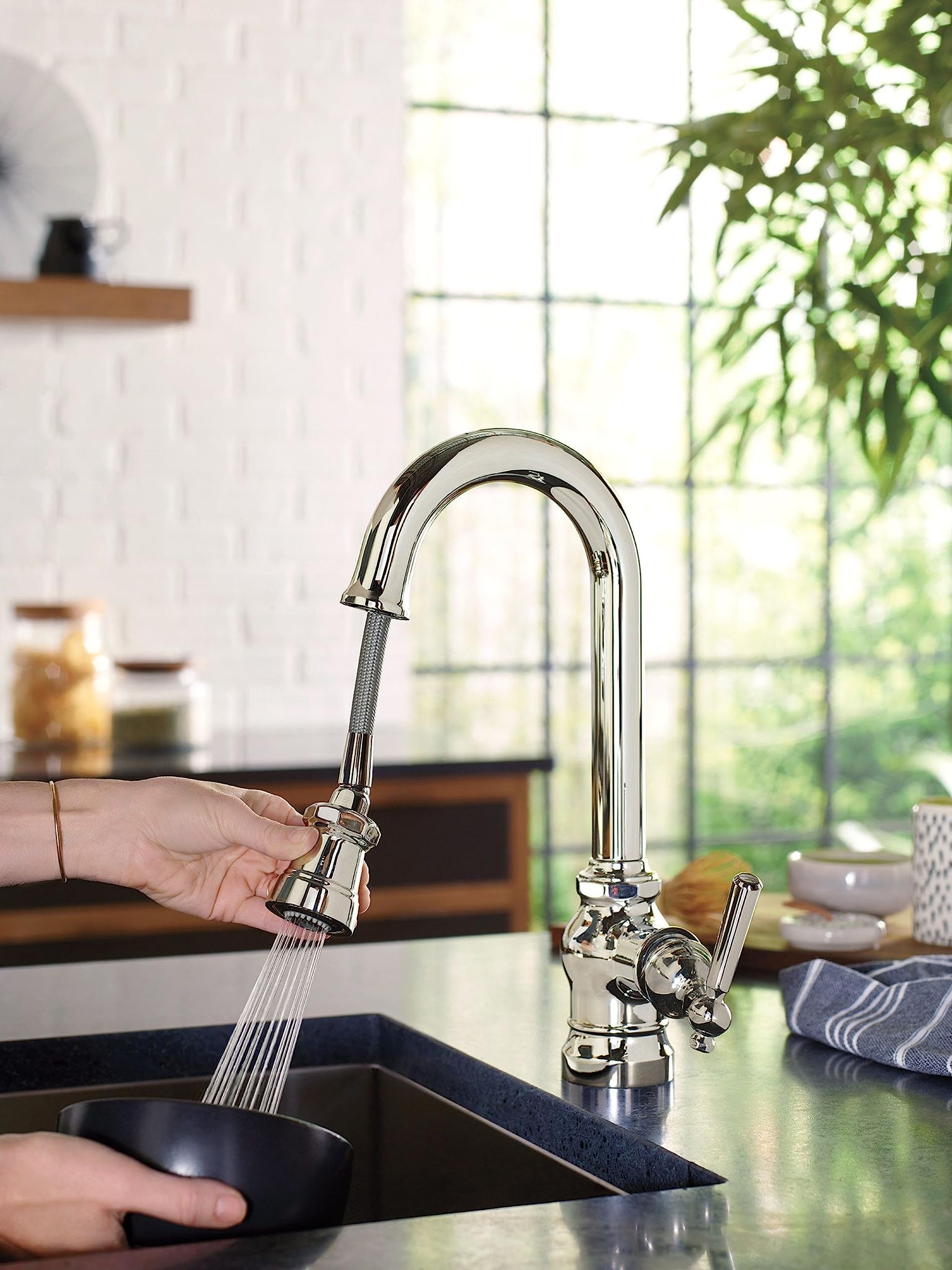 Chrome pulldown bar faucet with single handle extended over sink, water stream visible.
