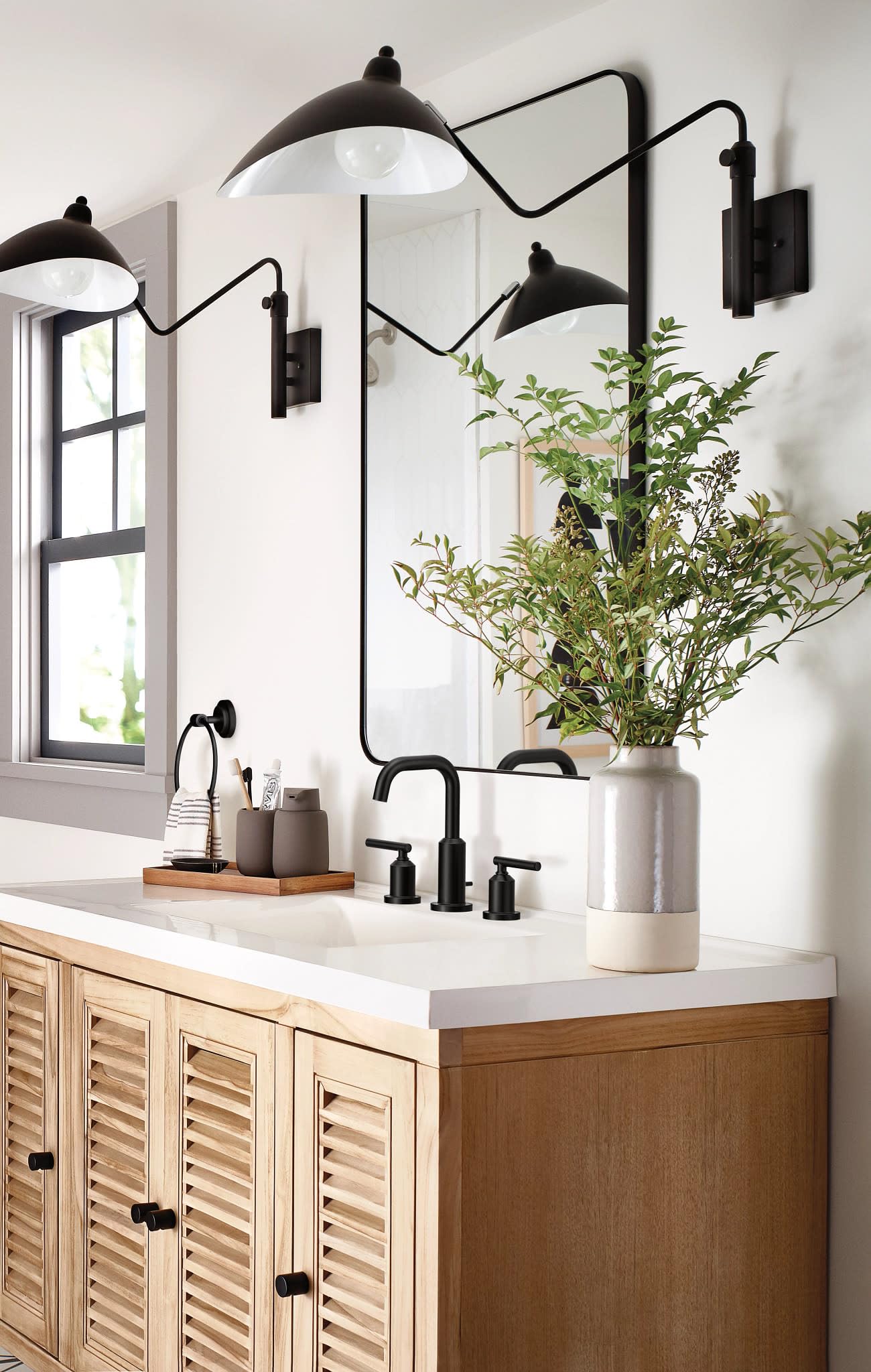Matte black widespread faucet trim with curved spout and dual handles installed on bathroom vanity sink.