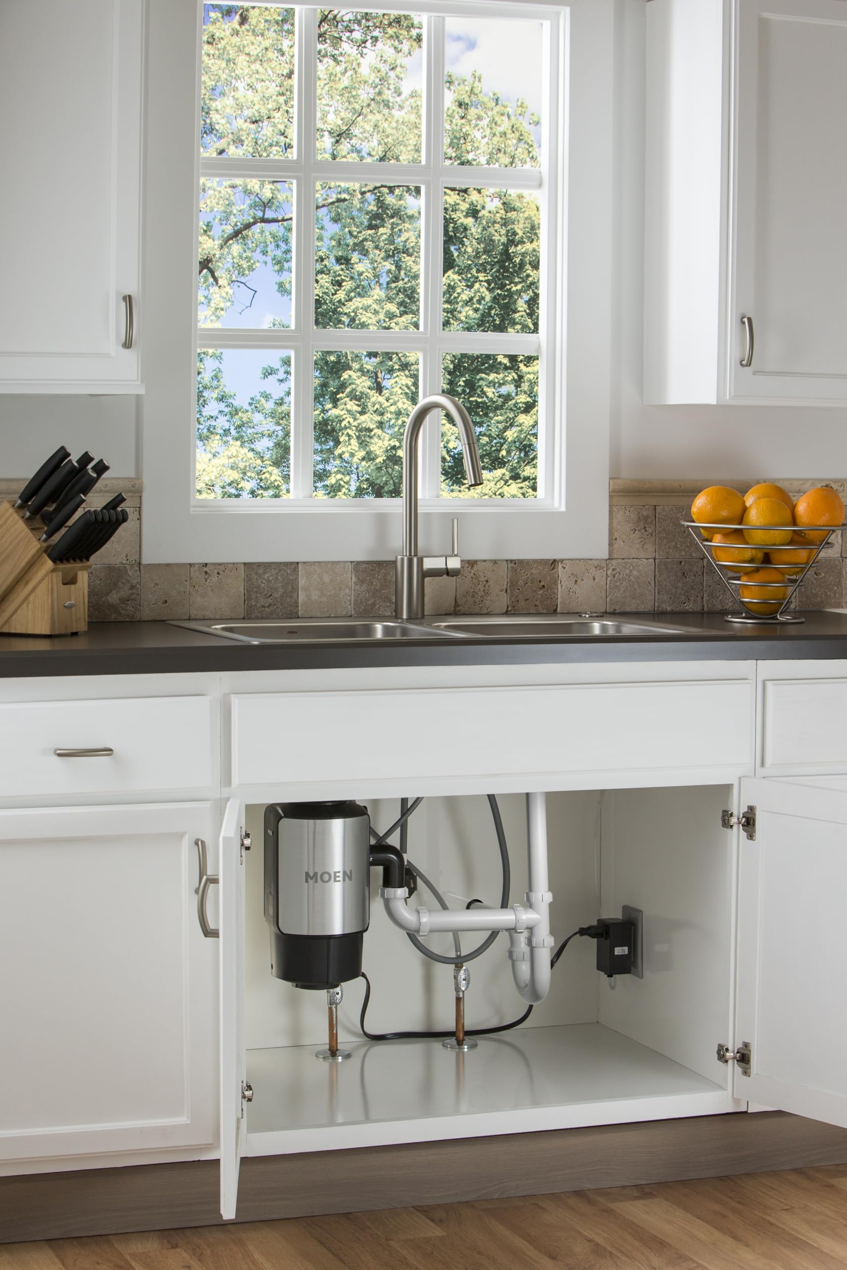 Stainless steel pulldown kitchen faucet with curved spout installed above sink in white cabinet.
