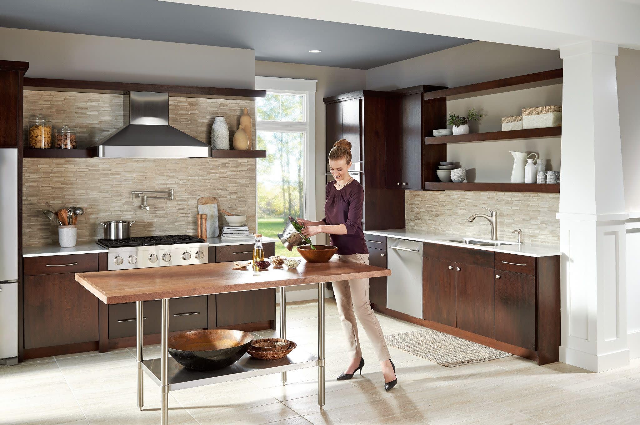 Stainless steel wall-mounted swing arm faucet with double-jointed folding design installed above kitchen sink.