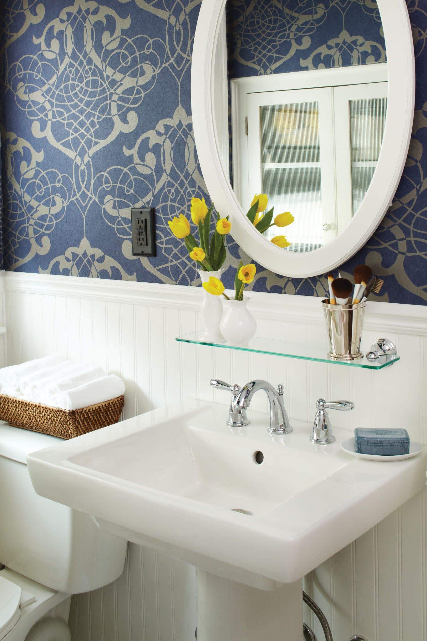 Chrome two-handle widespread faucet with curved spout installed on white pedestal sink.