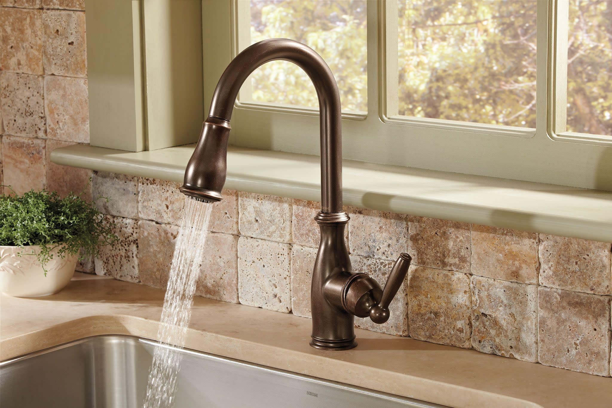 Oil rubbed bronze pull-down kitchen faucet with curved spout and side handle, shown installed above sink.