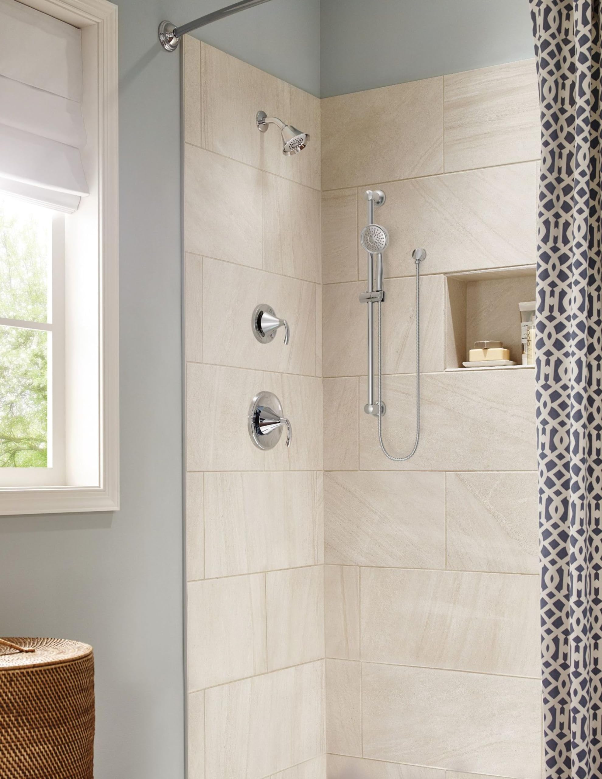 Chrome shower faucet with round showerhead and handheld spray on beige tile wall in bathroom.