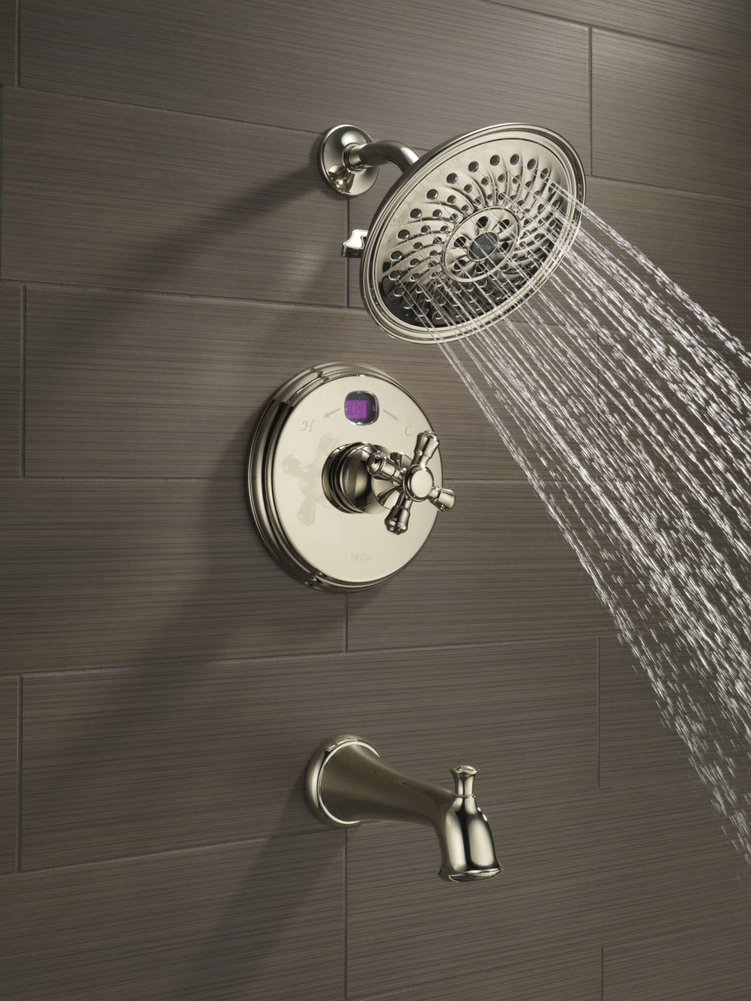 Chrome tub spout with pull-up diverter mounted on tile wall below shower head and valve control.