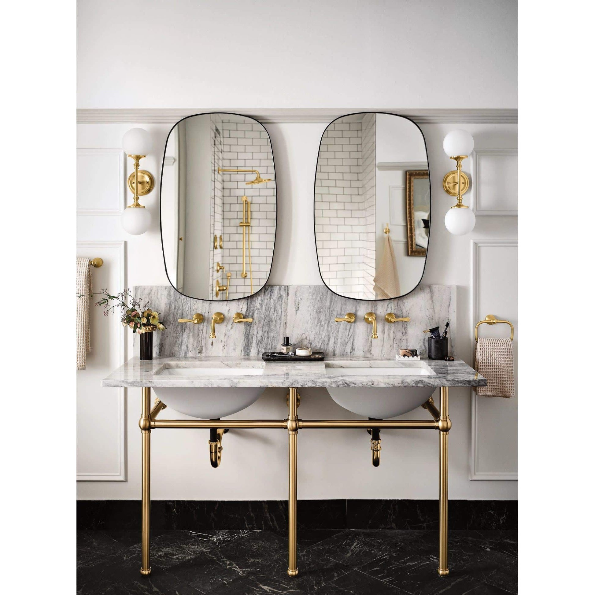 Matte black wall-mounted bathroom faucet trim with traditional lever handles installed above marble countertop sink.