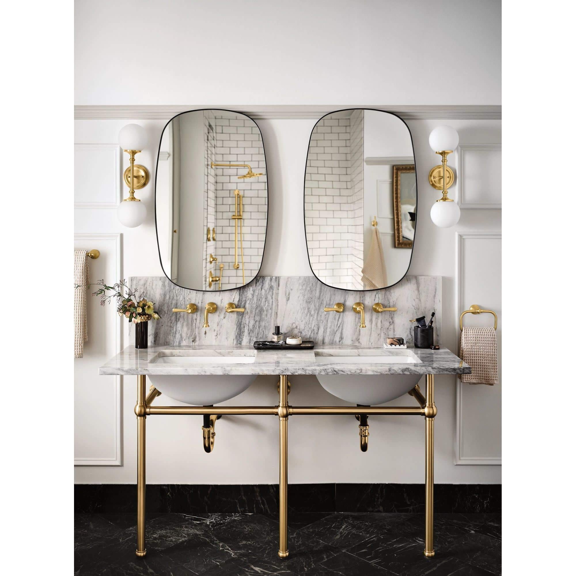 Matte black wall-mounted bathroom faucet trim with traditional lever handles installed above marble countertop sink.