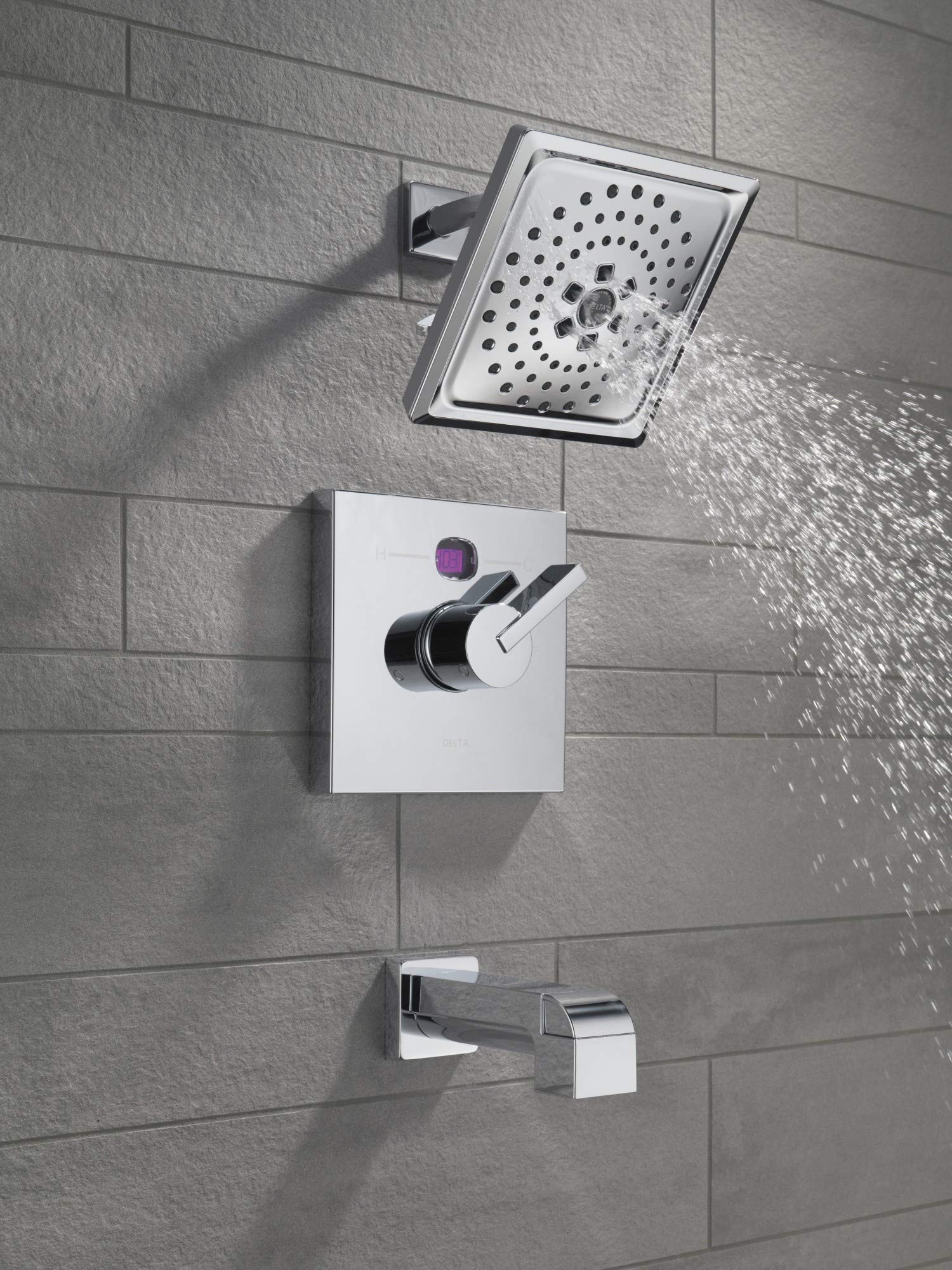Chrome tub spout with pull-up diverter mounted on gray tile wall below showerhead.