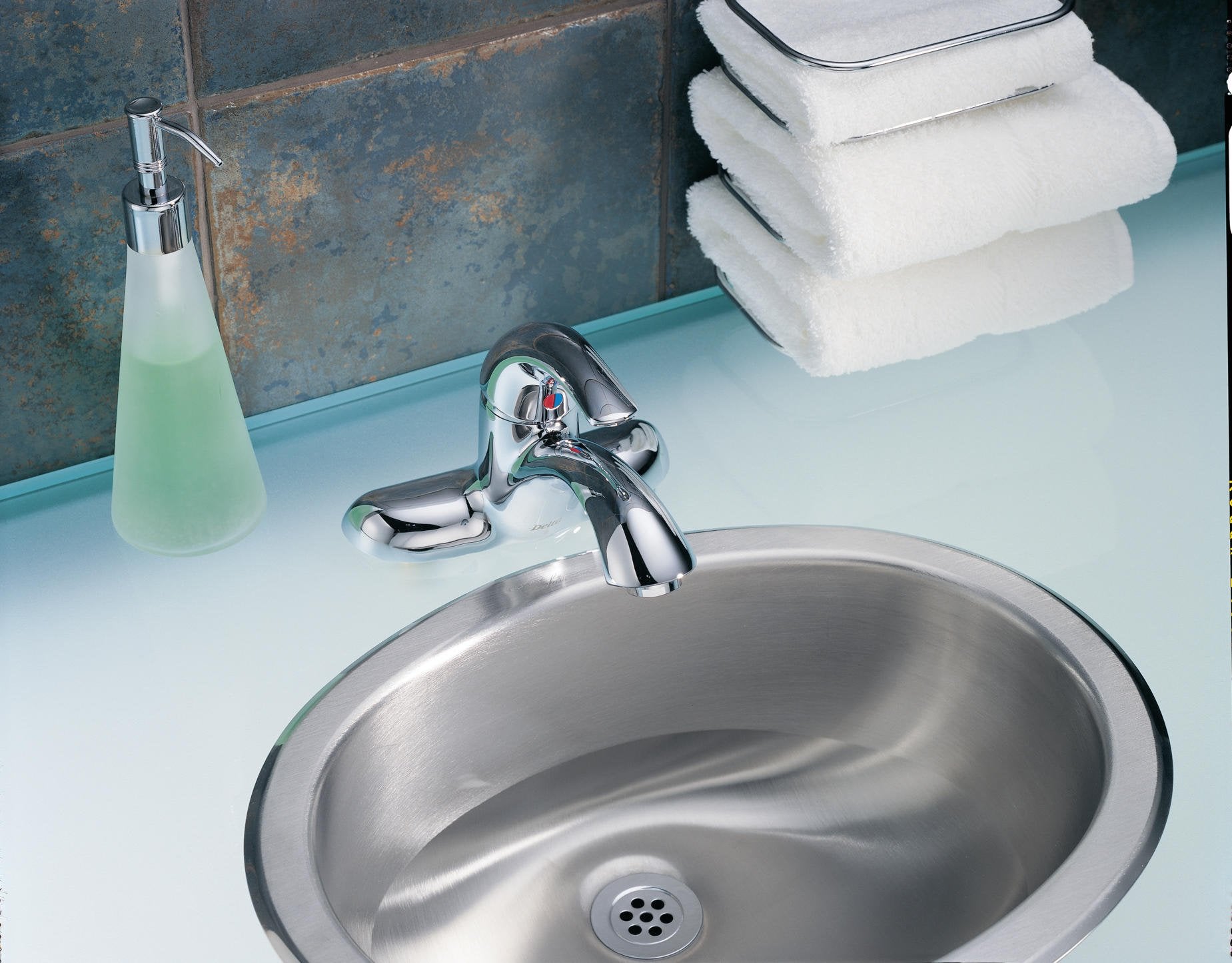 Chrome single handle centerset bathroom faucet with lever control mounted above stainless steel sink basin.