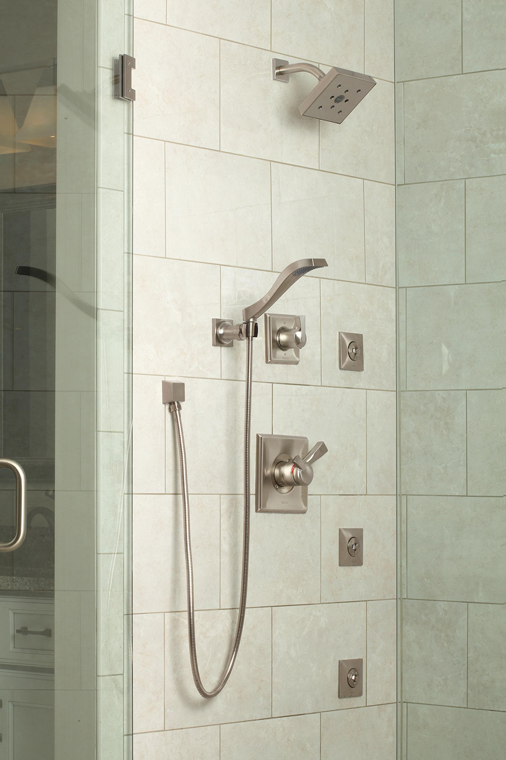 Stainless steel square wall elbow mounted on tile shower wall with hand shower and hose connection.