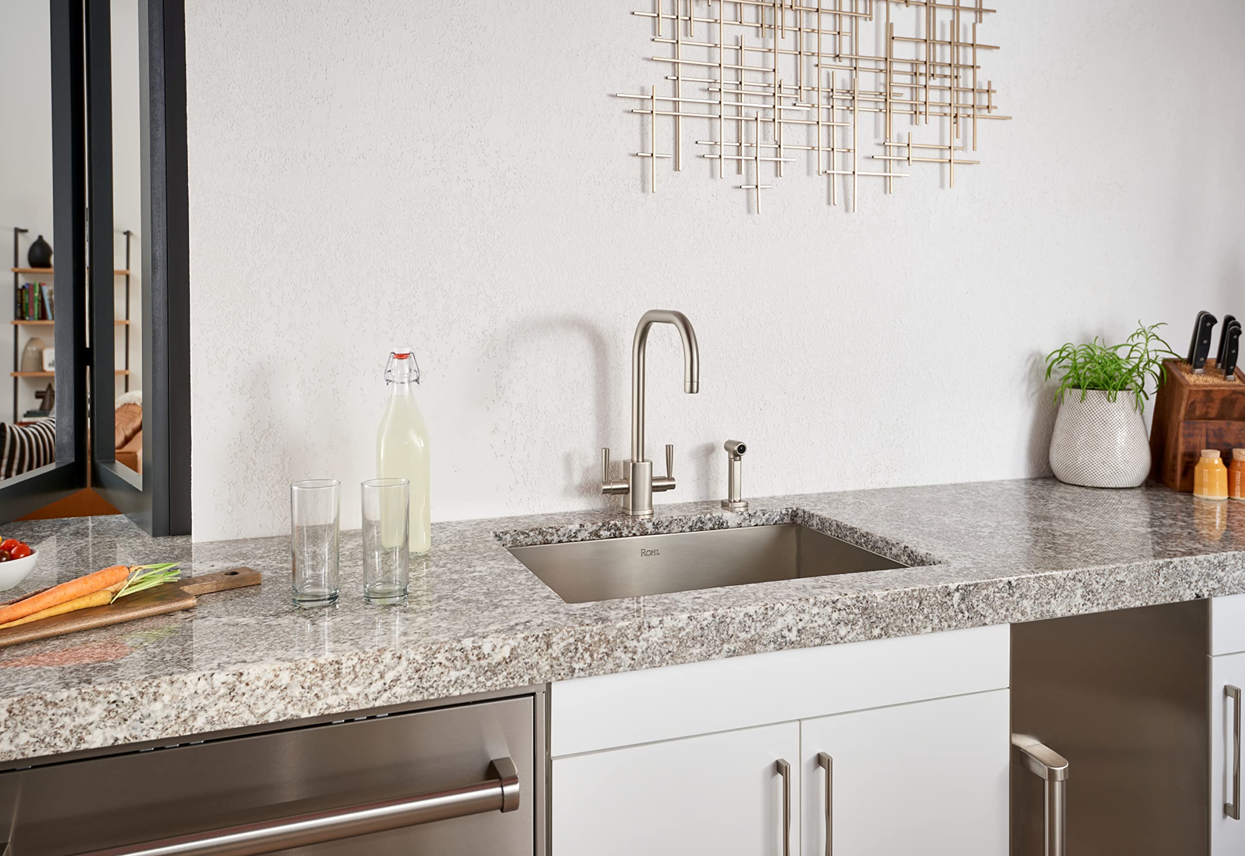 Black stainless steel single bowl kitchen sink installed in granite countertop with faucet and accessories.