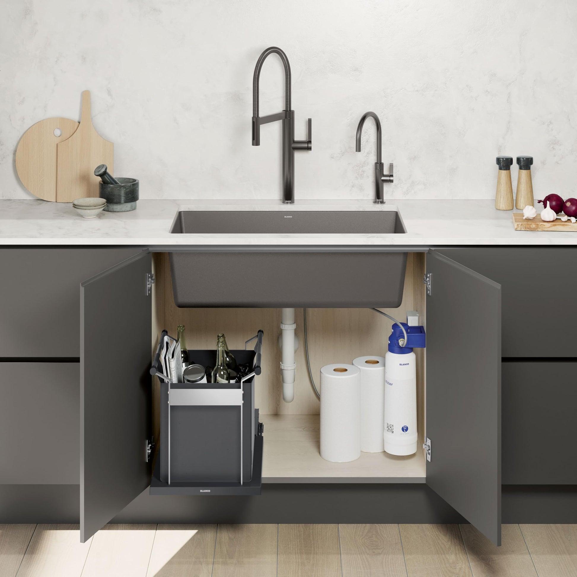 Black storage bag with handles sits under kitchen sink alongside paper towels and cleaning supplies.