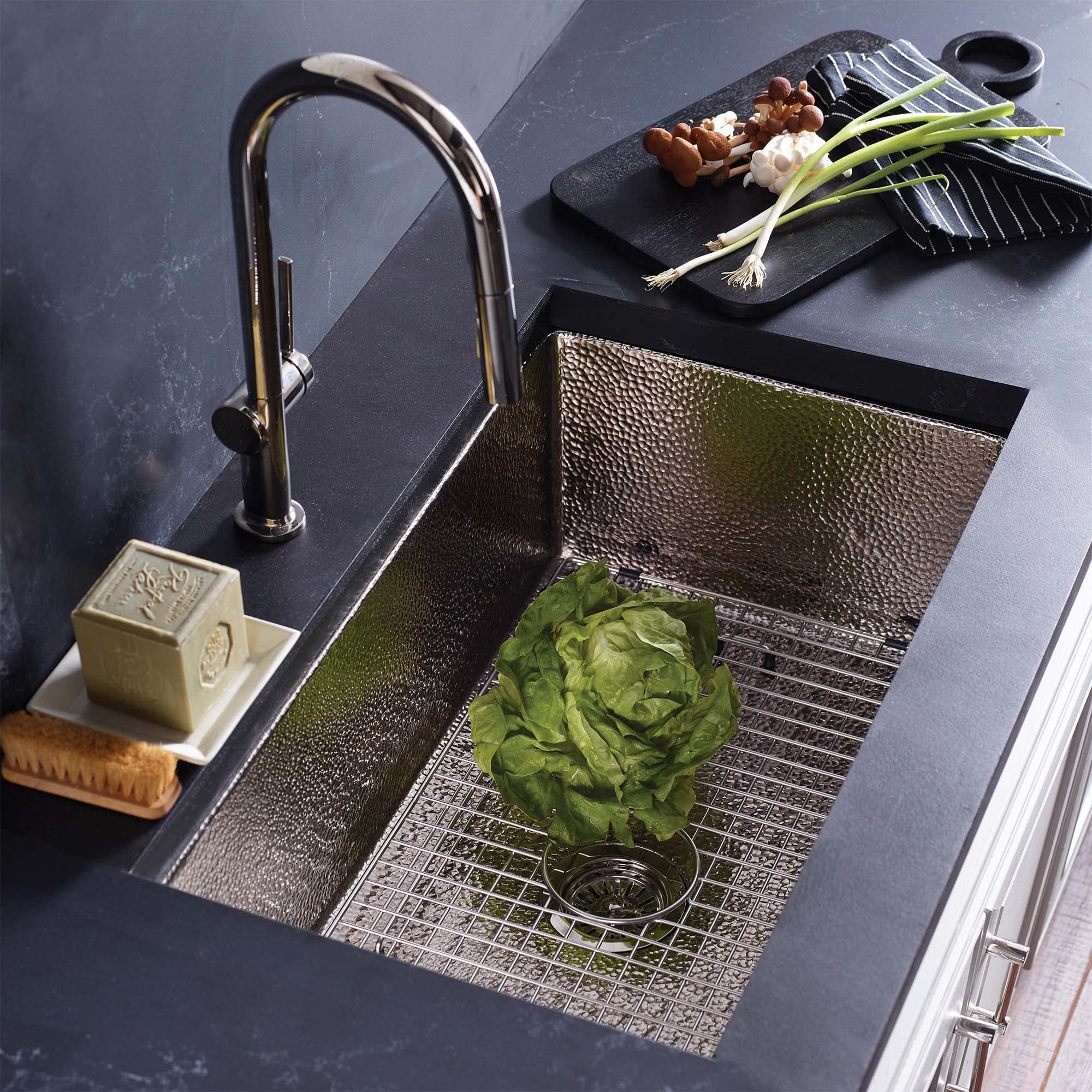 Brushed nickel undermount kitchen sink with hammered interior basin and grid insert, paired with matching faucet.