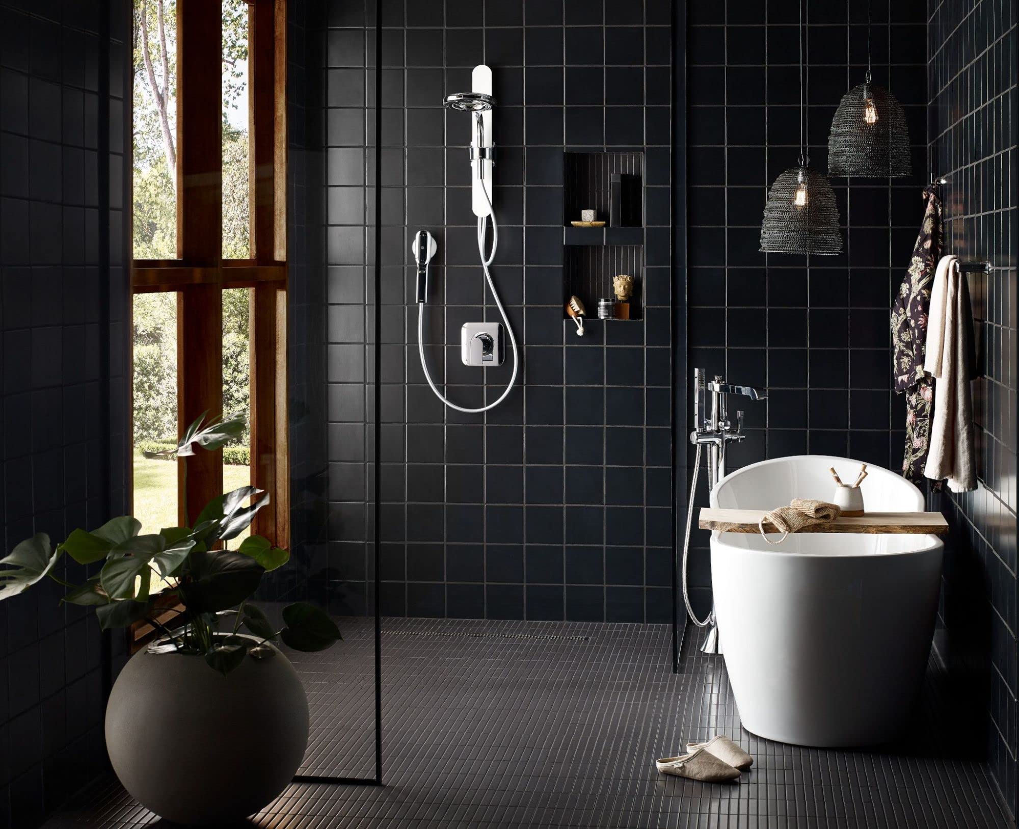 Chrome freestanding floor mount tub filler with single handle and attached handheld showerhead in bathroom setting.