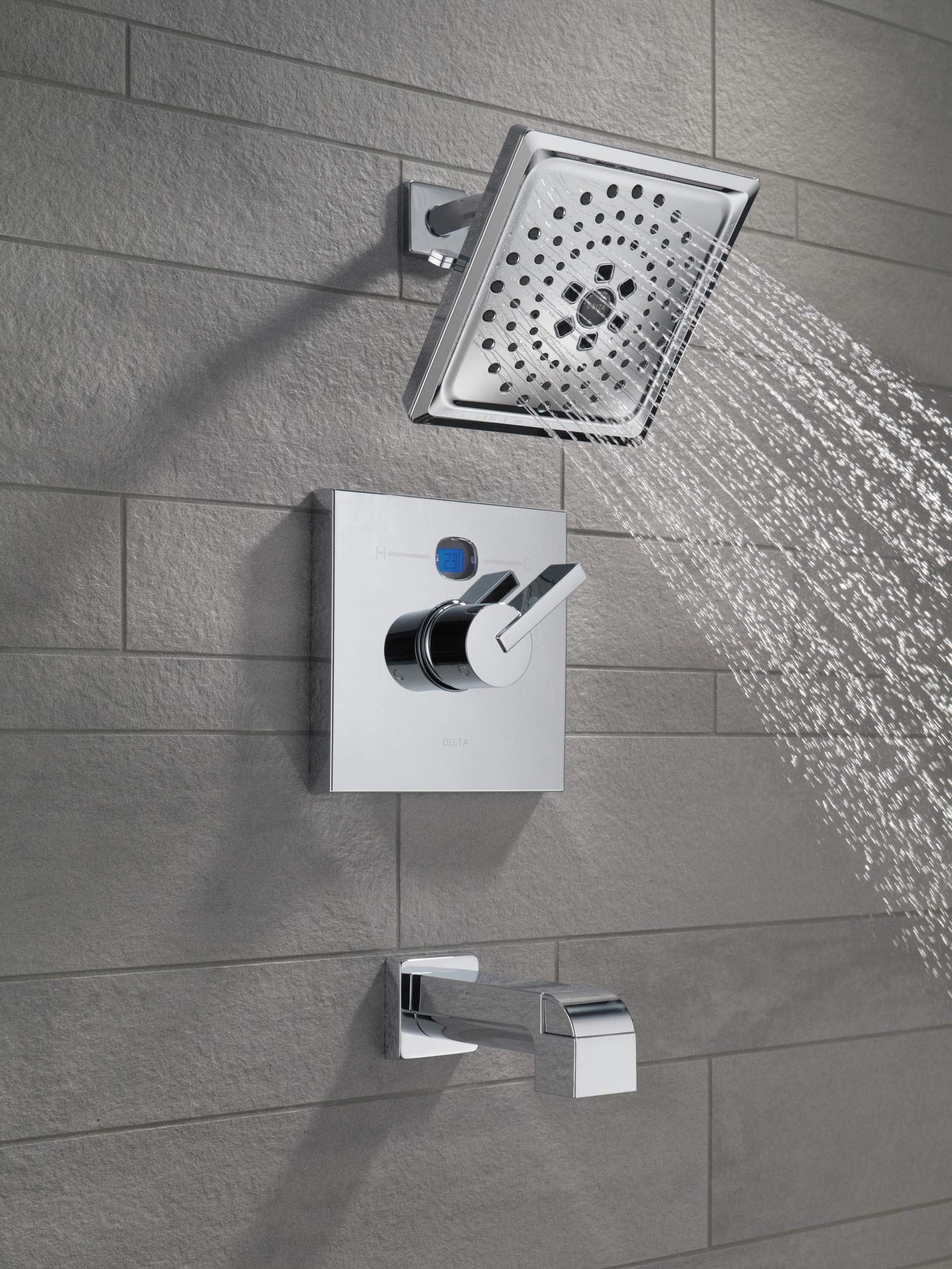 Black stainless steel shower arm with rectangular head mounted on tile wall, water streaming from perforated nozzle.