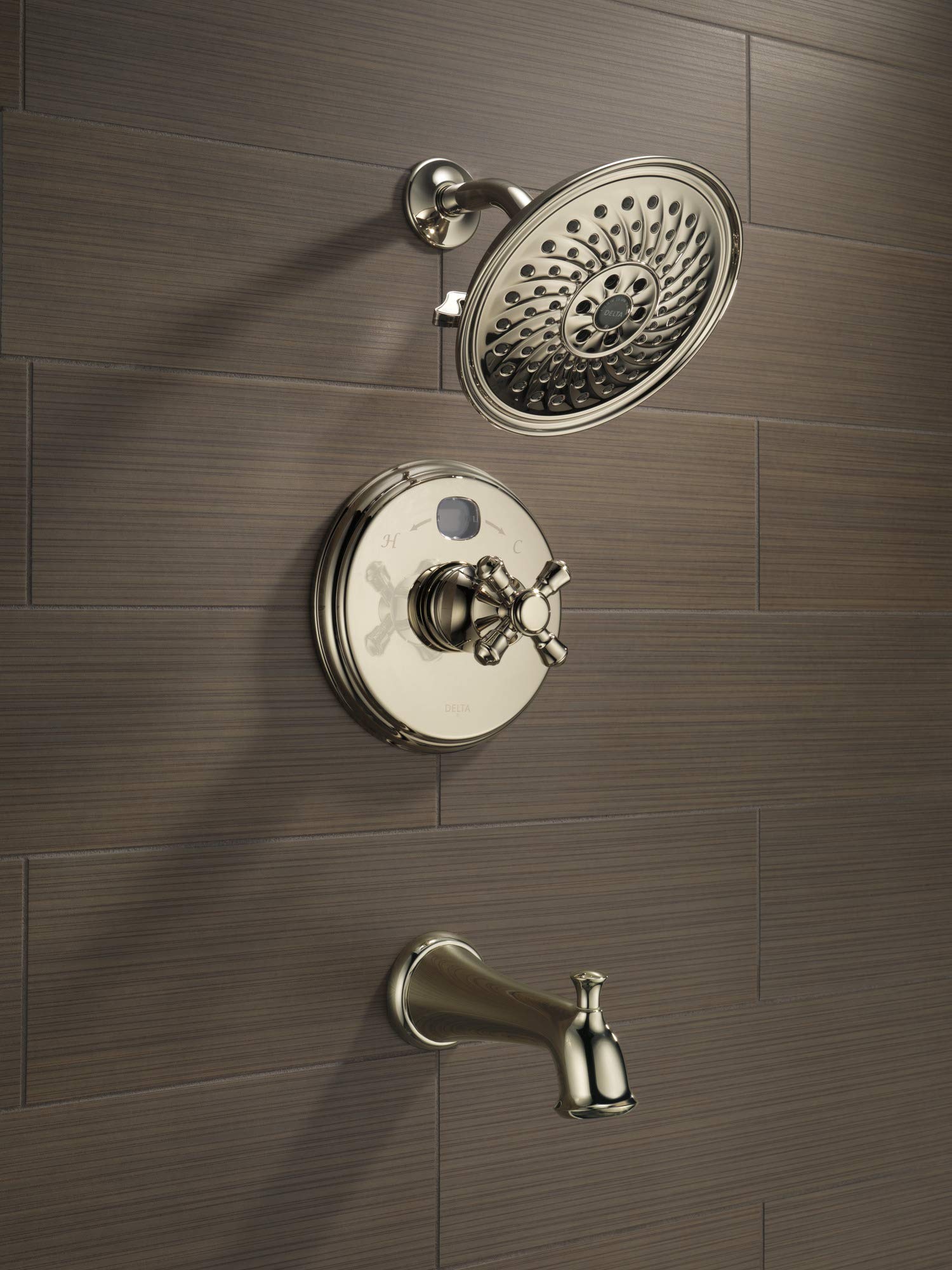 Polished nickel shower system mounted on tile wall with overhead rainfall showerhead, valve trim plate with cross handle, and