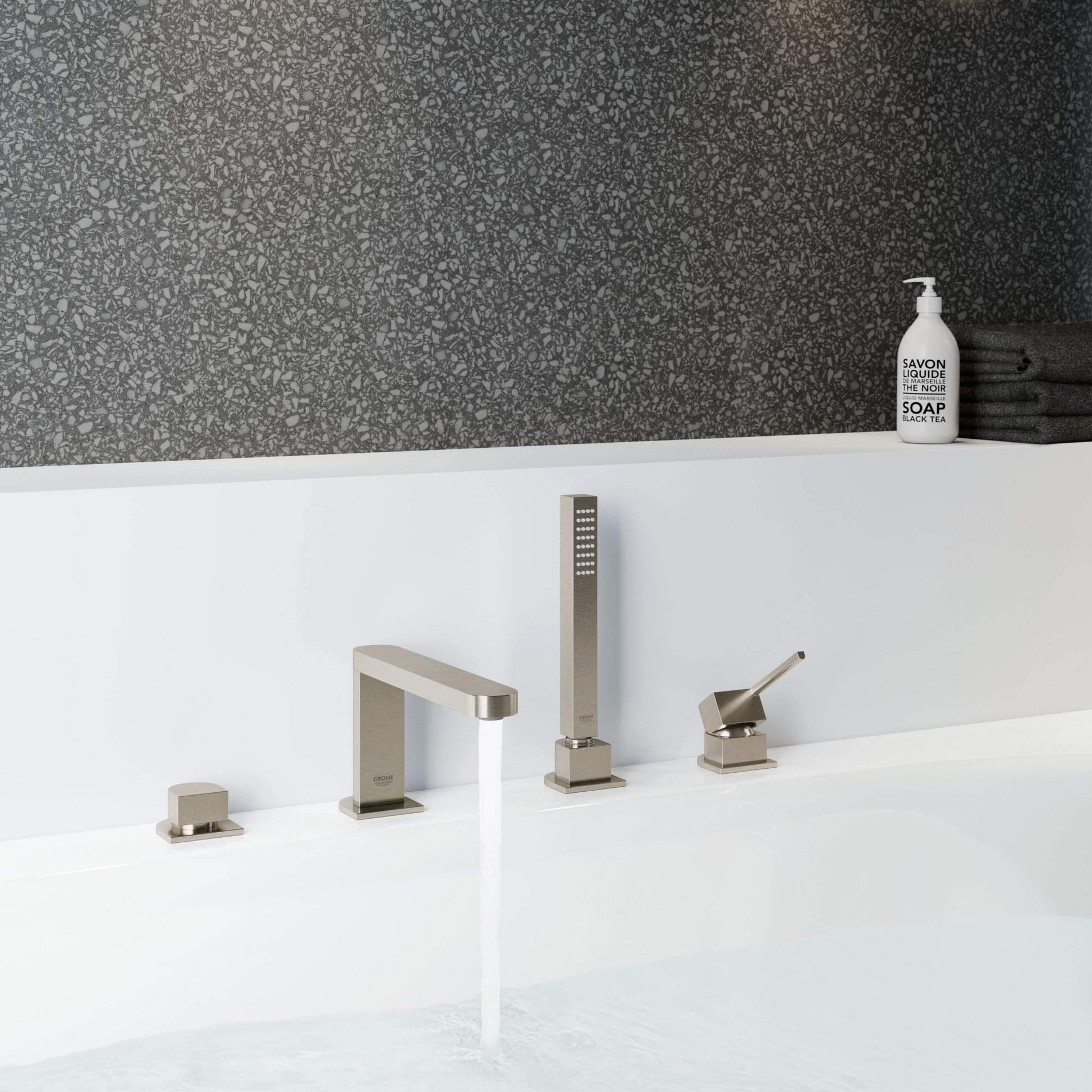 Brushed nickel four-piece tub faucet set with single handle spout, handheld shower, and two control knobs mounted on white de