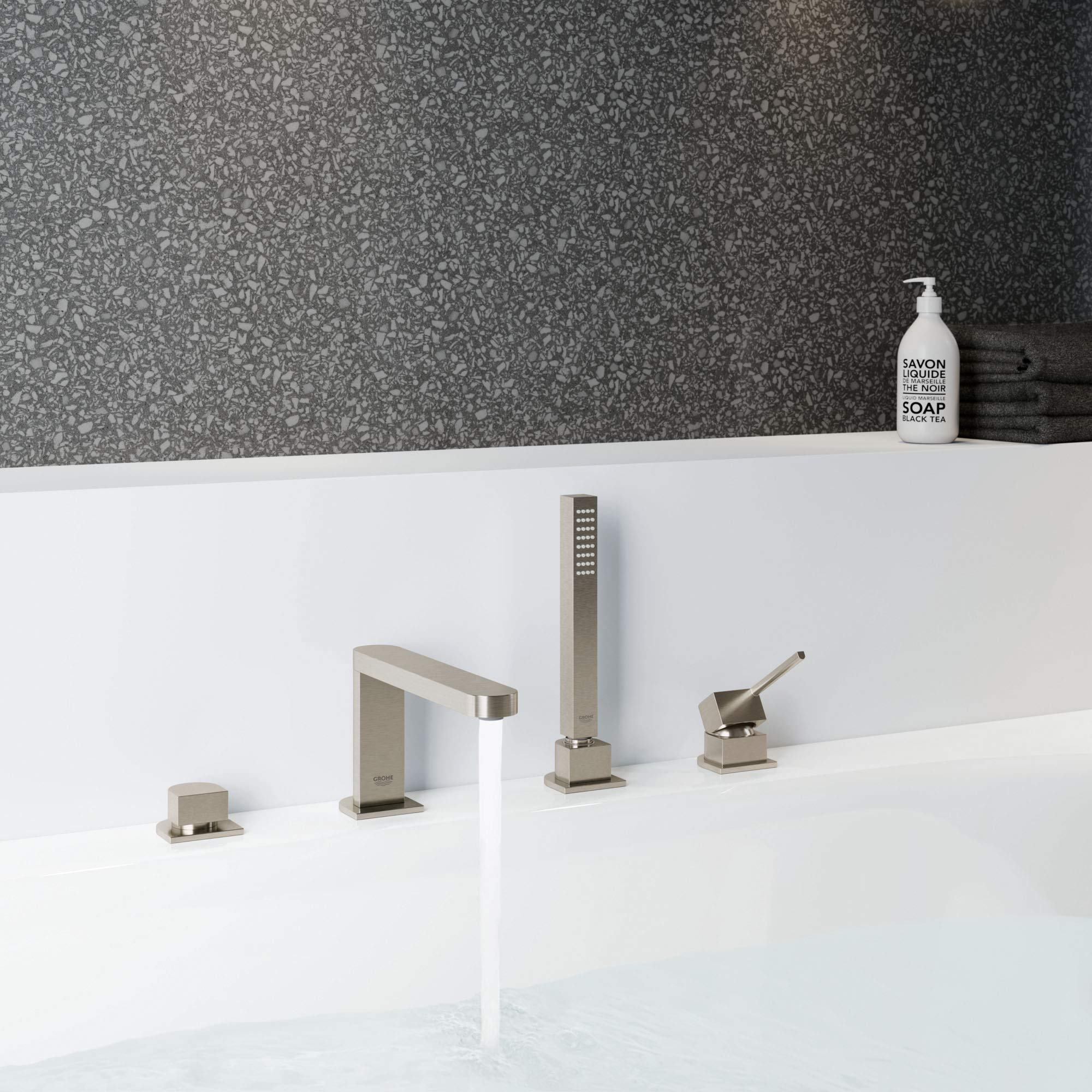 Brushed nickel four-piece tub faucet set with single handle spout, handheld shower, and two control knobs mounted on white de