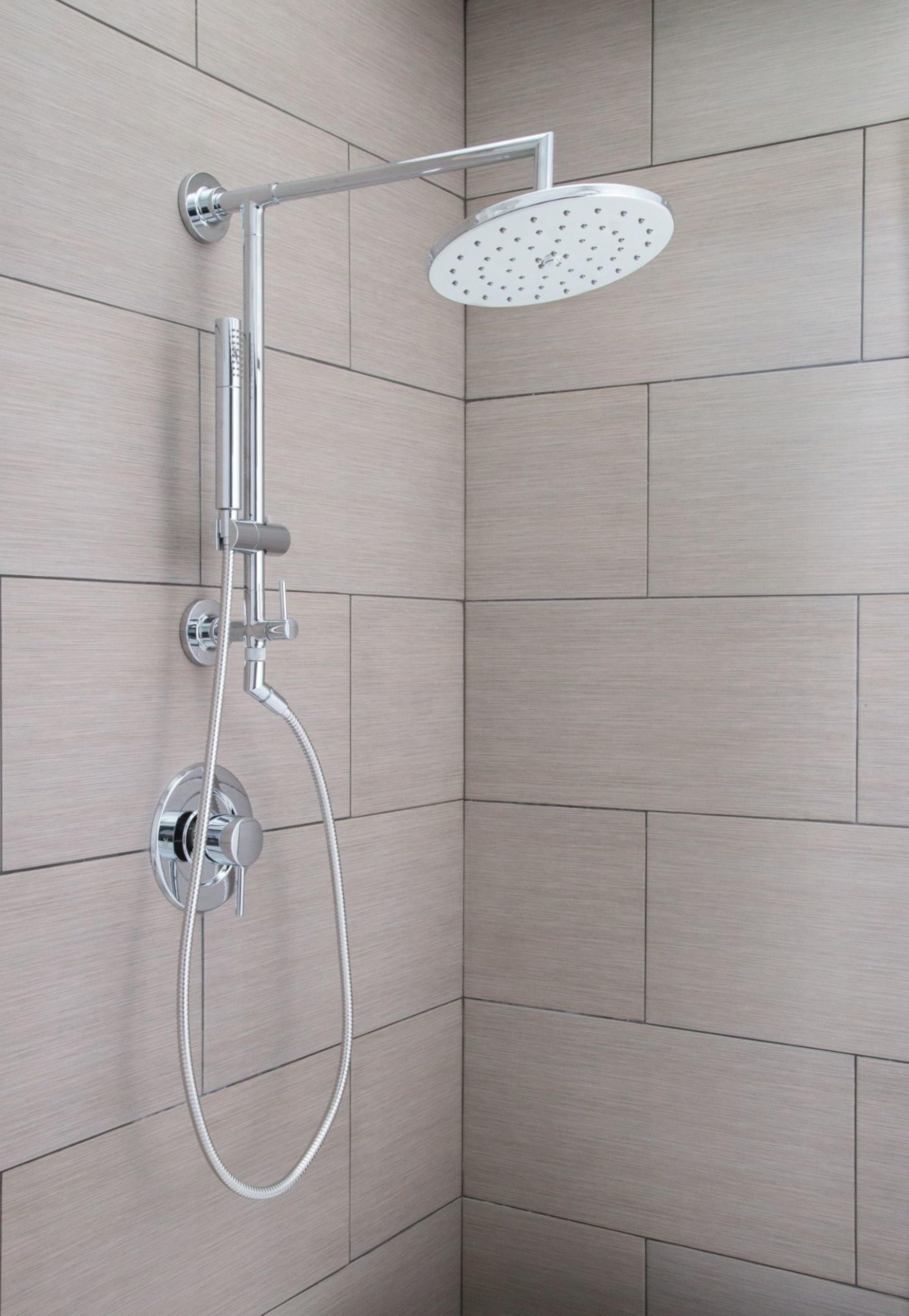 Chrome shower system with overhead rainfall showerhead, adjustable slidebar, handheld hose, and valve controls mounted on til
