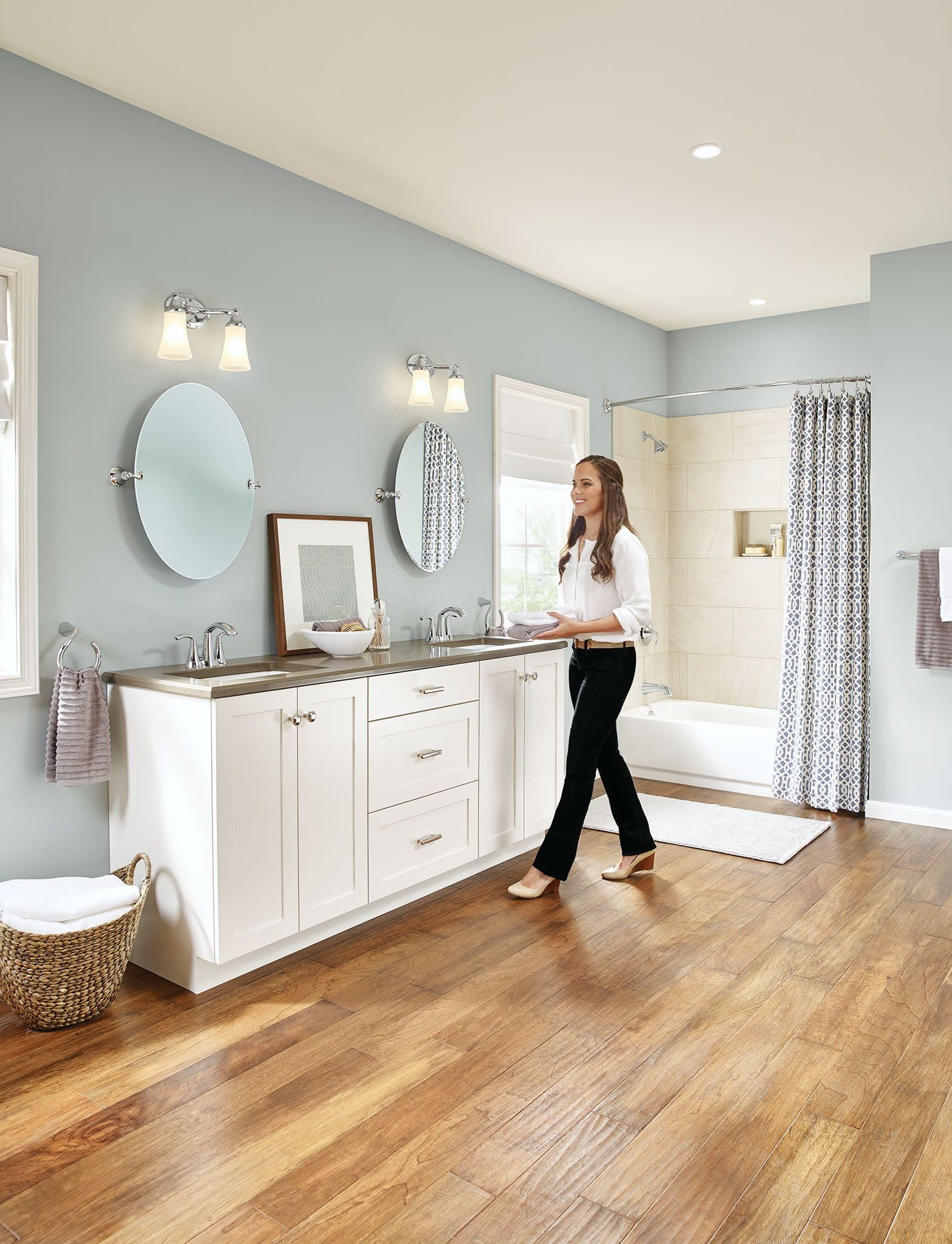 Chrome two-handle high arc bathroom faucet with curved spout installed on bathroom vanity.