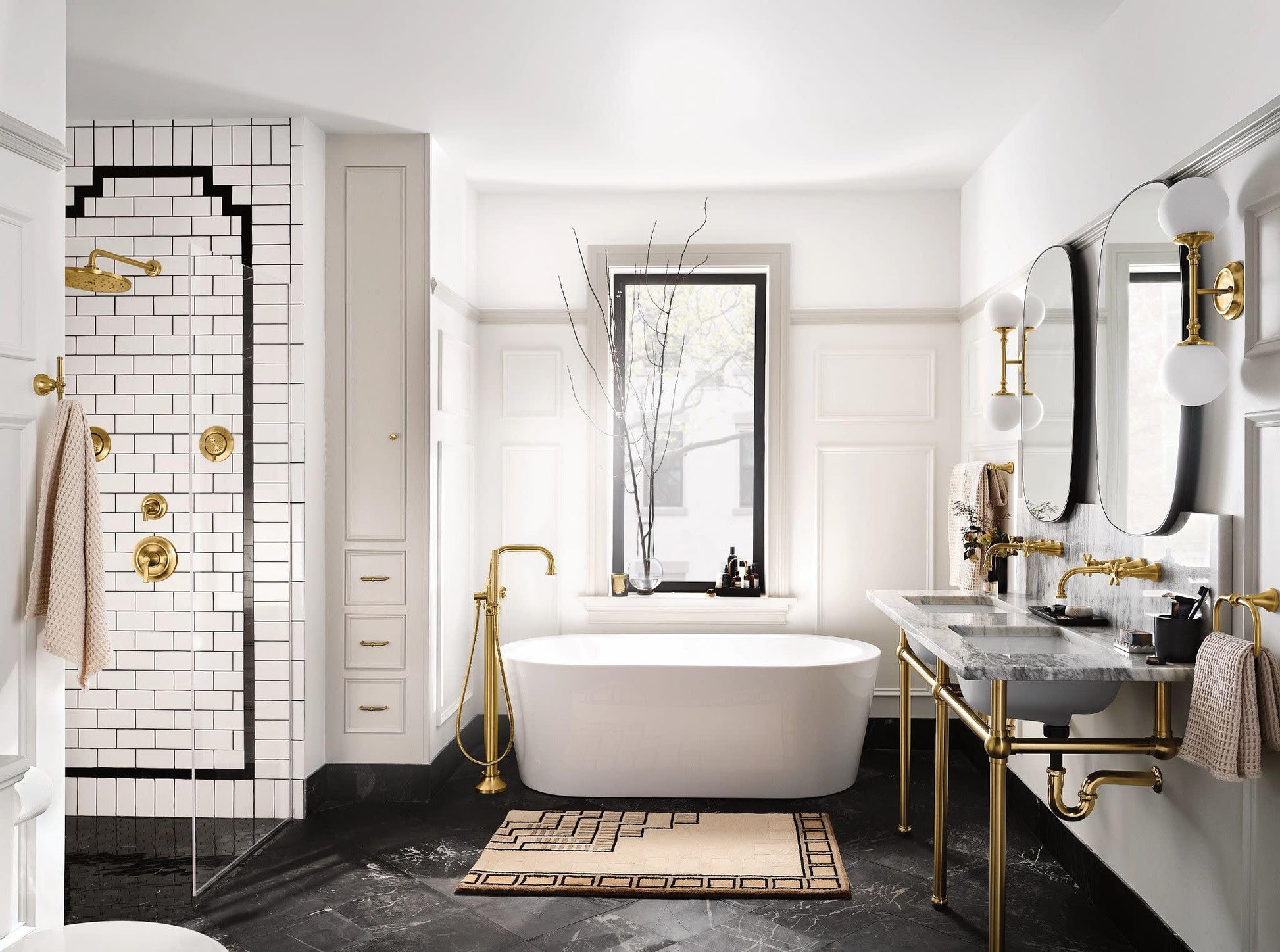 Brushed gold single-handle shower trim kit mounted on white subway tile shower wall with black grout lines.