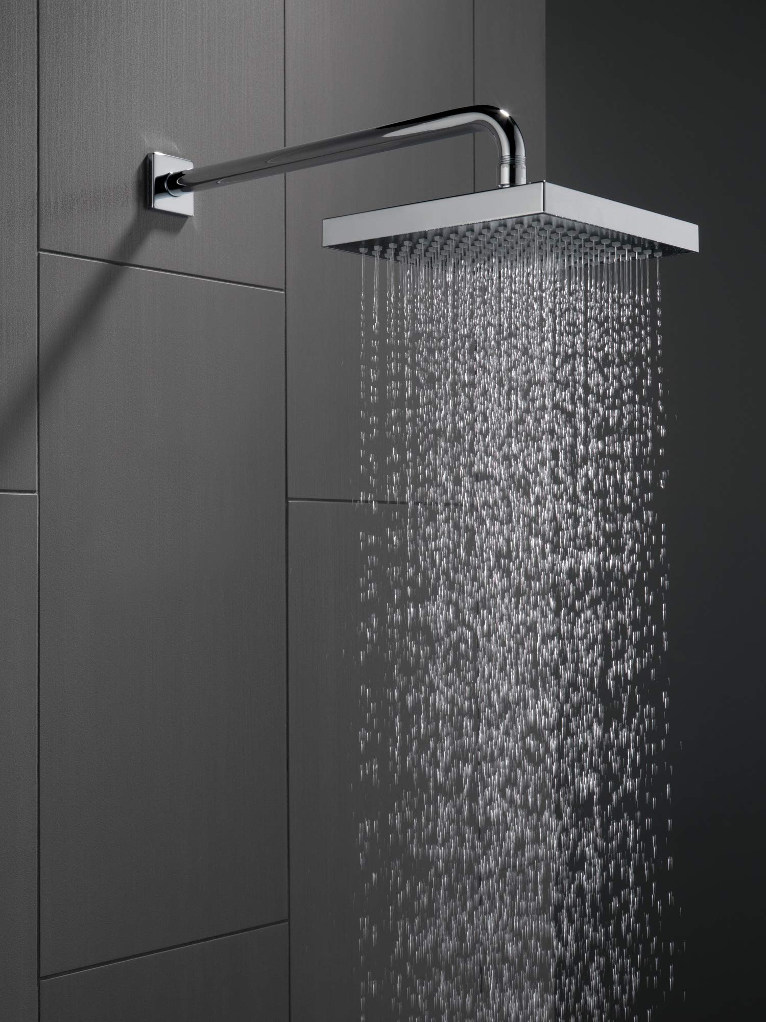 Black stainless steel shower arm extending from wall mount to square showerhead with water flowing.